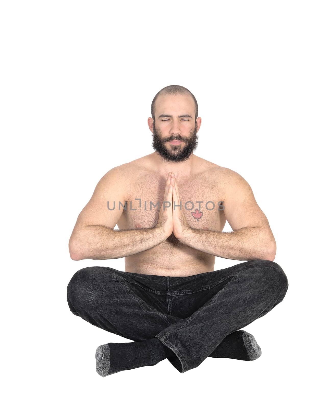 Man with beard sitting on the floor with his hands folded and eyes .closed meditating in a yoga pose, isolated for white background.