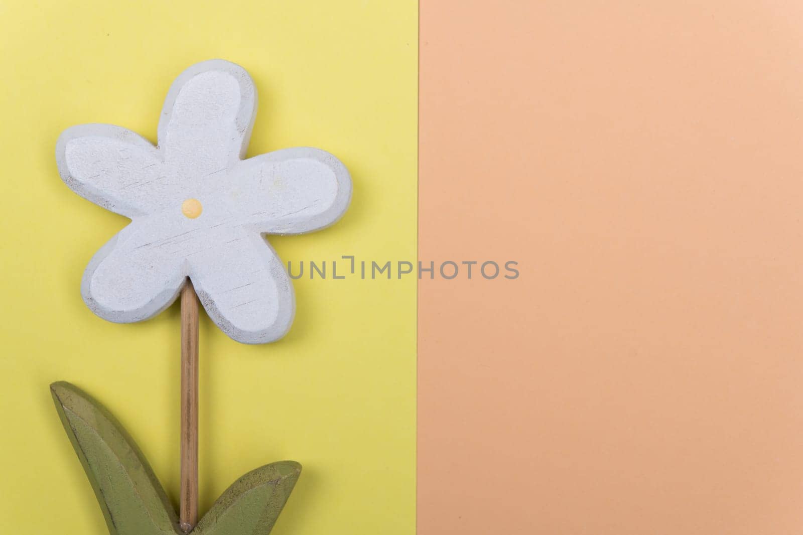 wooden marguerite flower on yellow and orange ground from above
