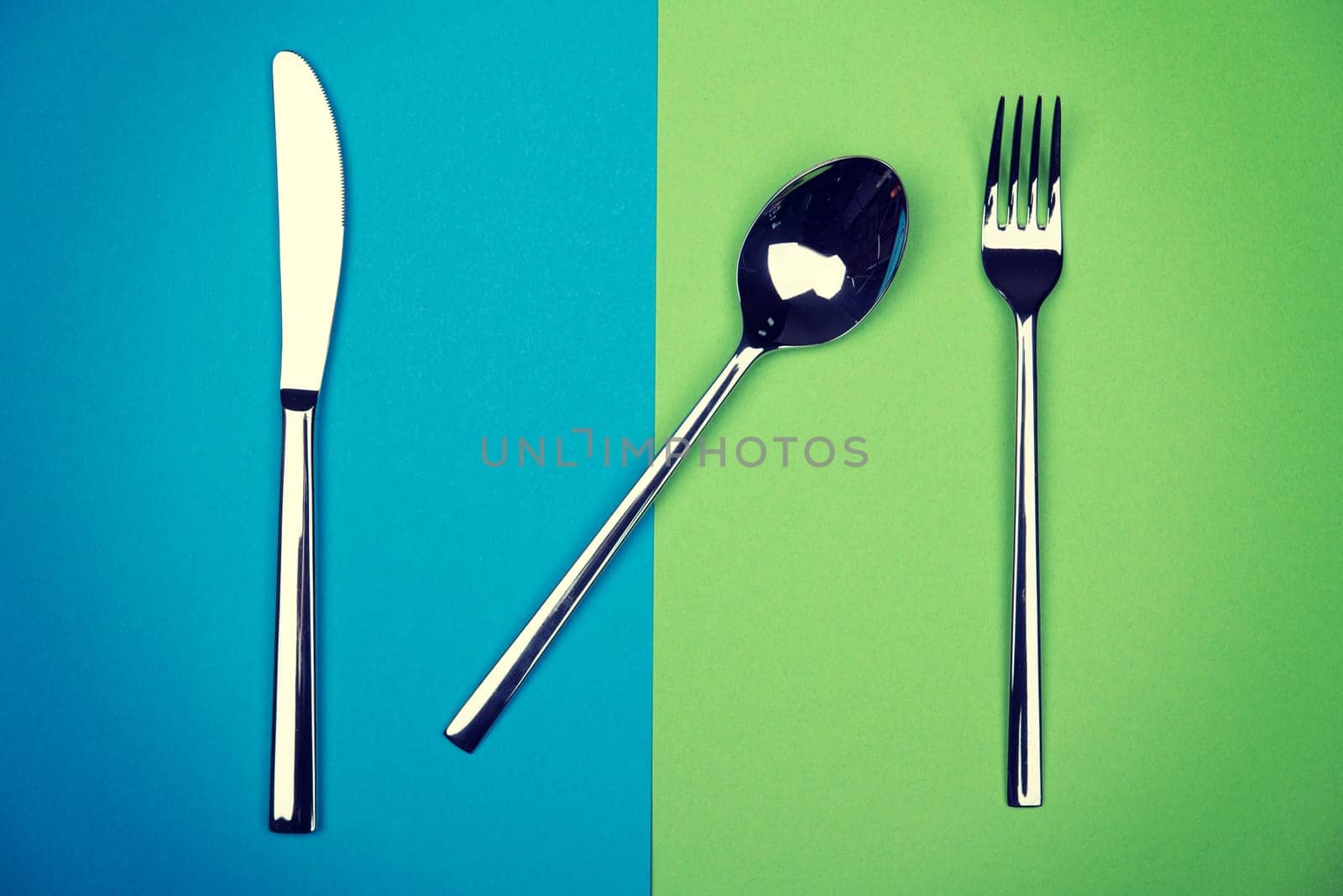 spoon, knife and fork on blue and green ground from above