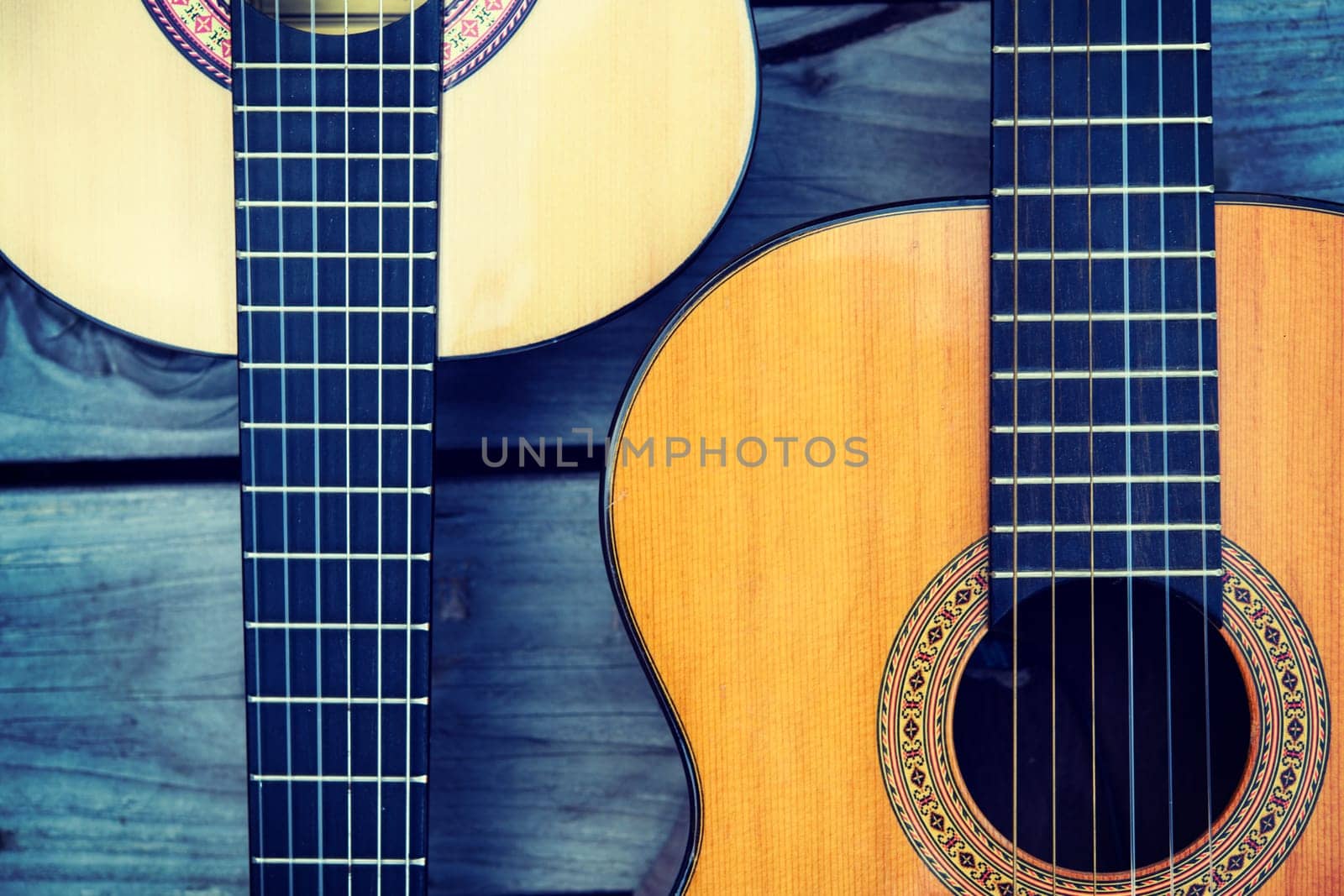 close up of two acoustic guitar on wooden ground