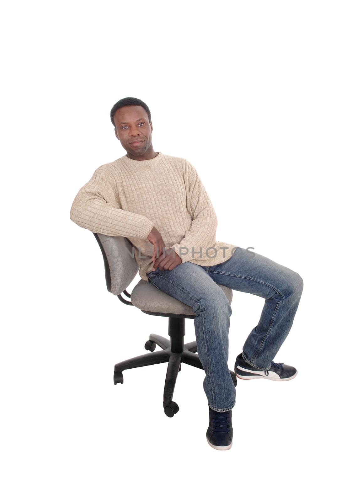 A full body image of a African American man in jeans and beige sweater.sitting on office chair, isolated for white background.