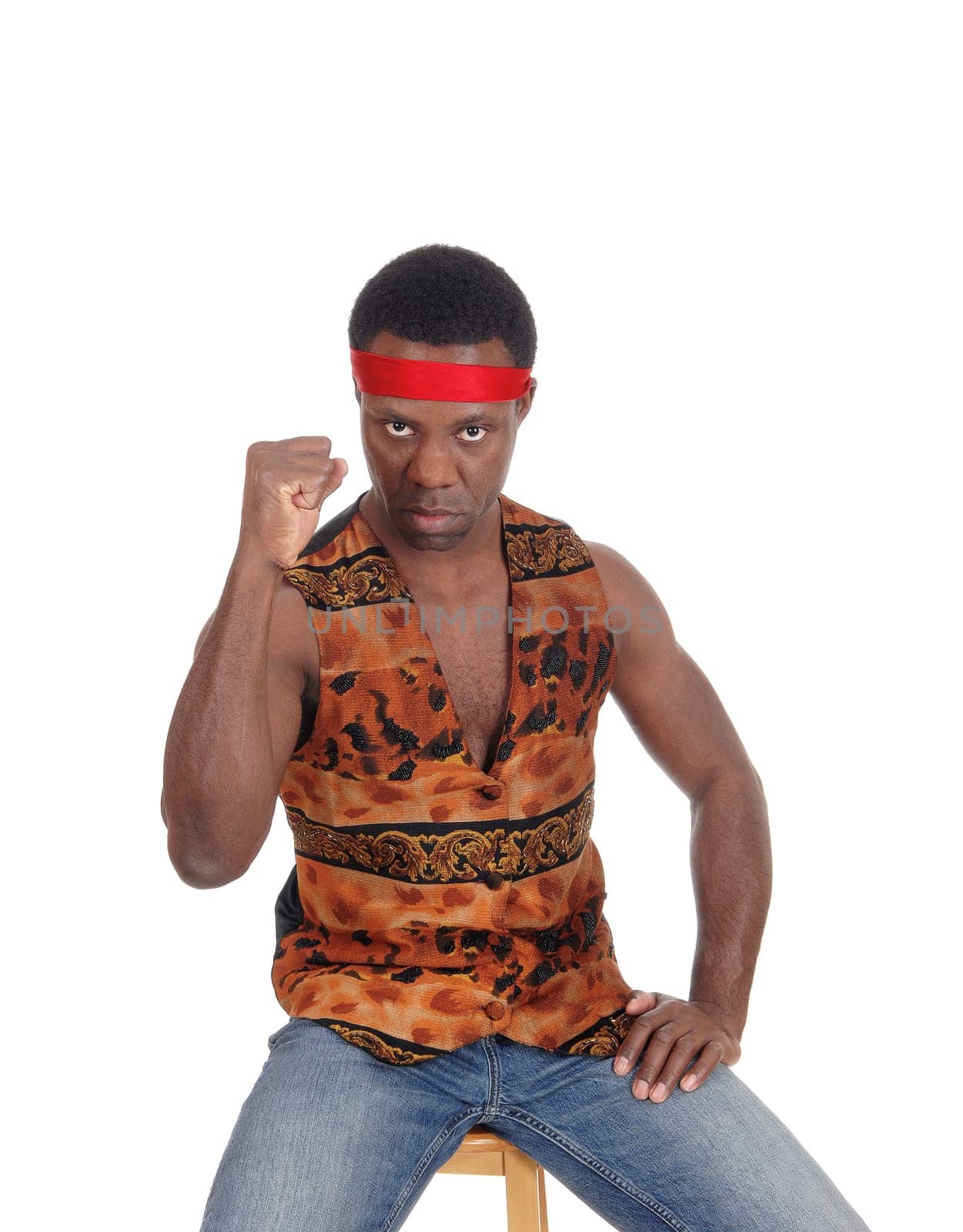 A handsome African American man sitting in a vest making a fist and .looking angry, isolated for white background.