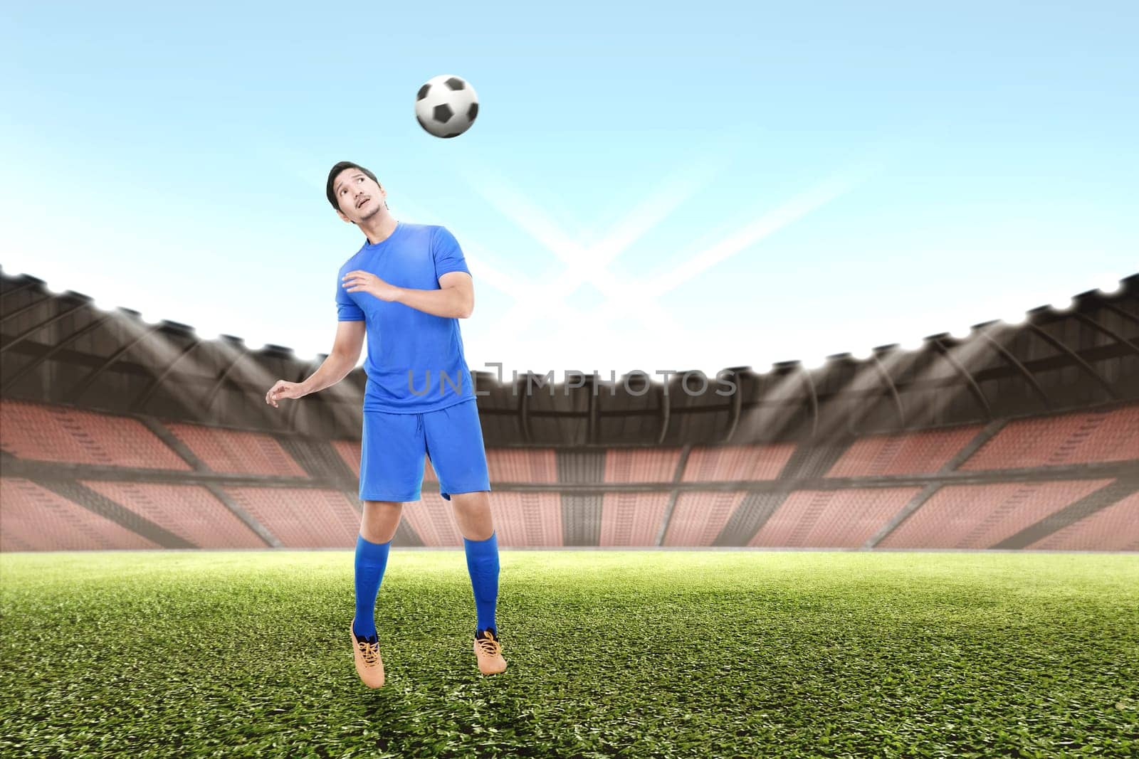 Young asian soccer player man jump and heading the ball on the field