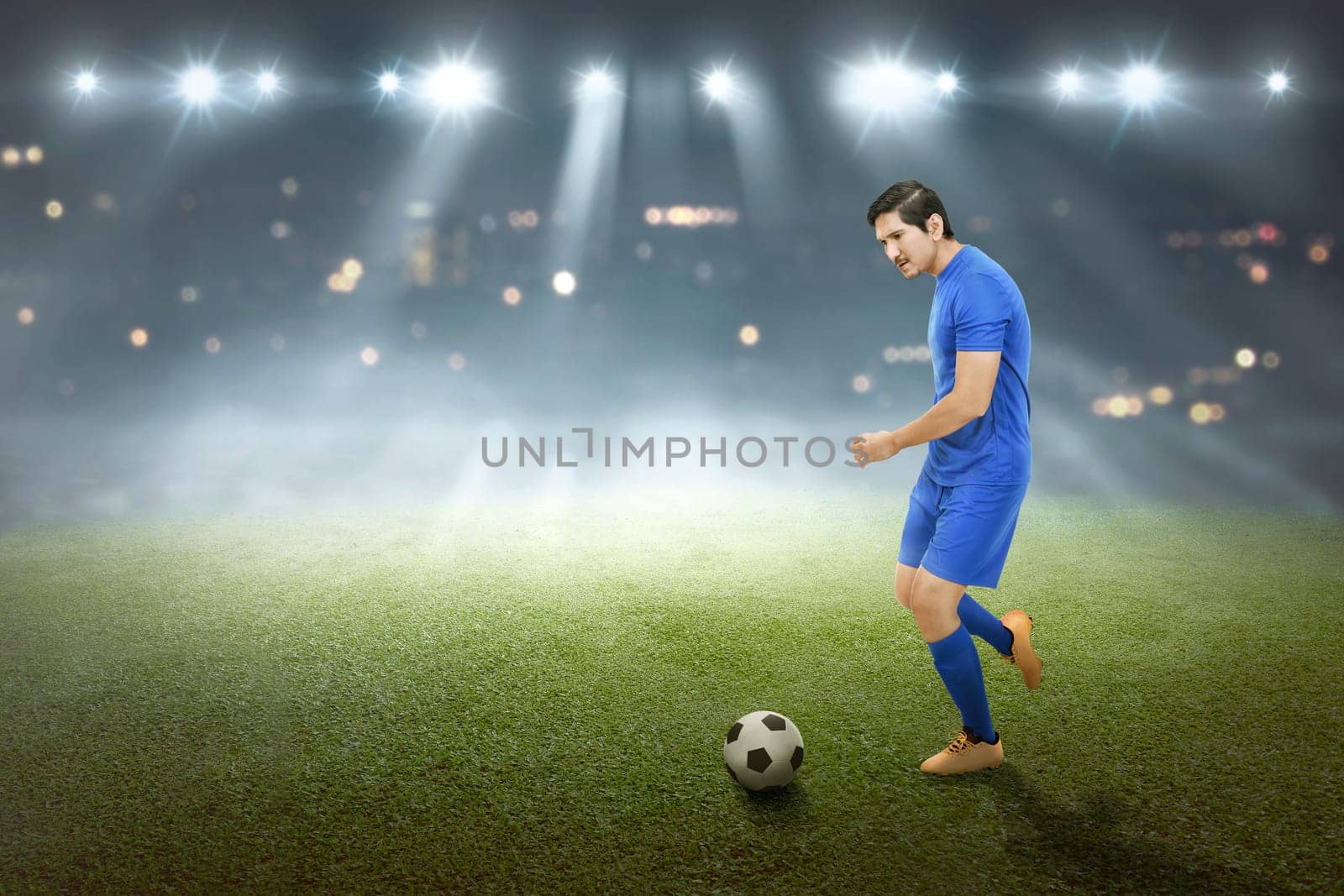 Spiritful asian male footballer kick the ball on the field