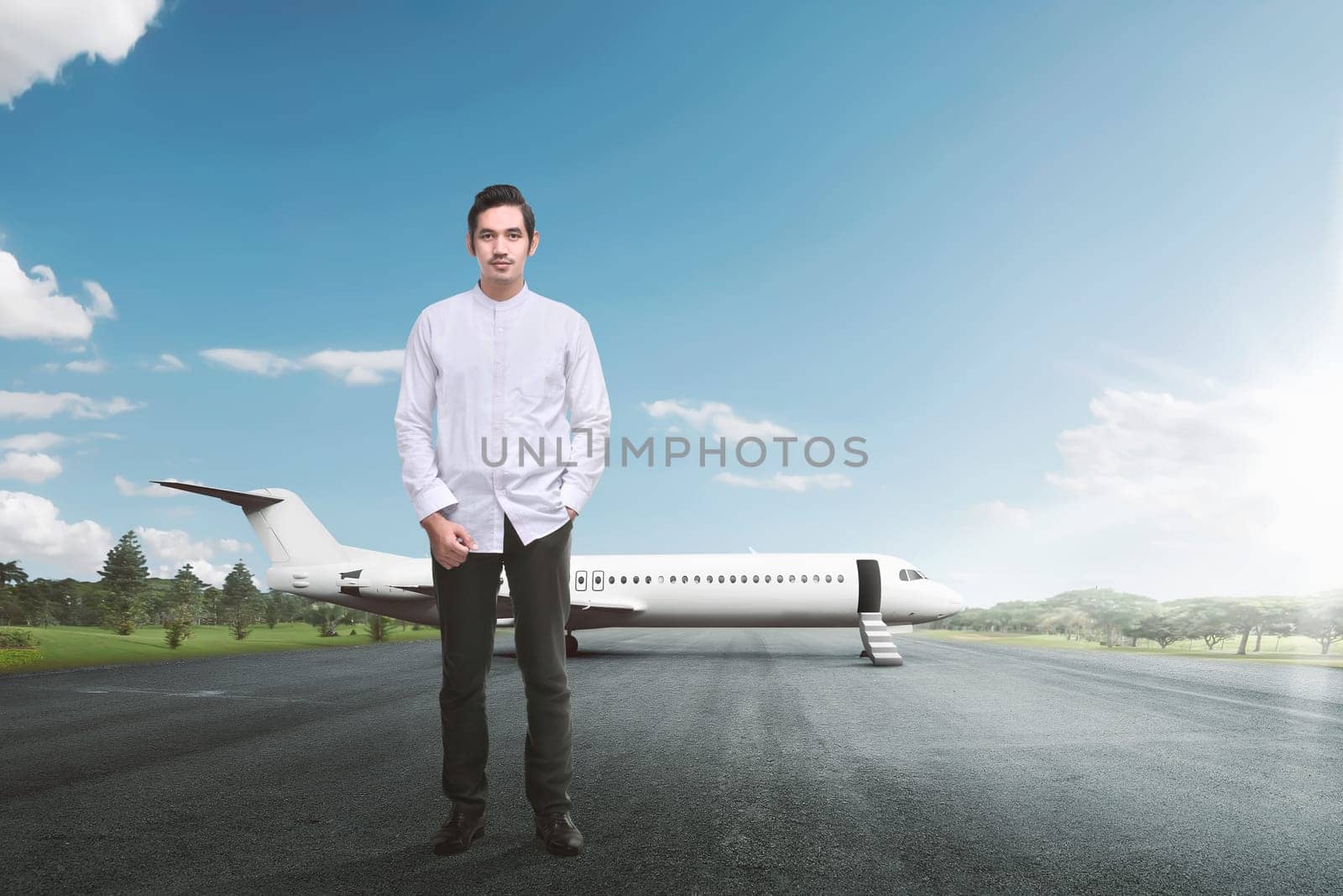 Handsome asian muslim man standing with airplane on the runway