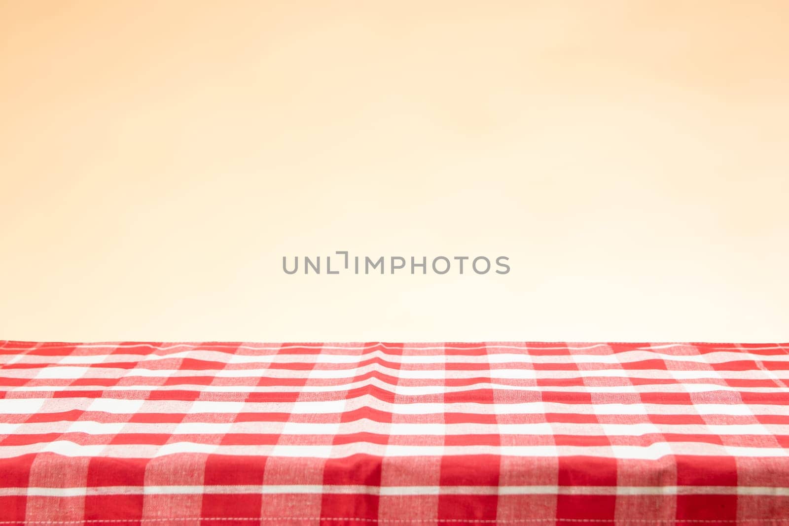 An empty table with a red checkered tablecloth and an bright background. For your food and product display montage.