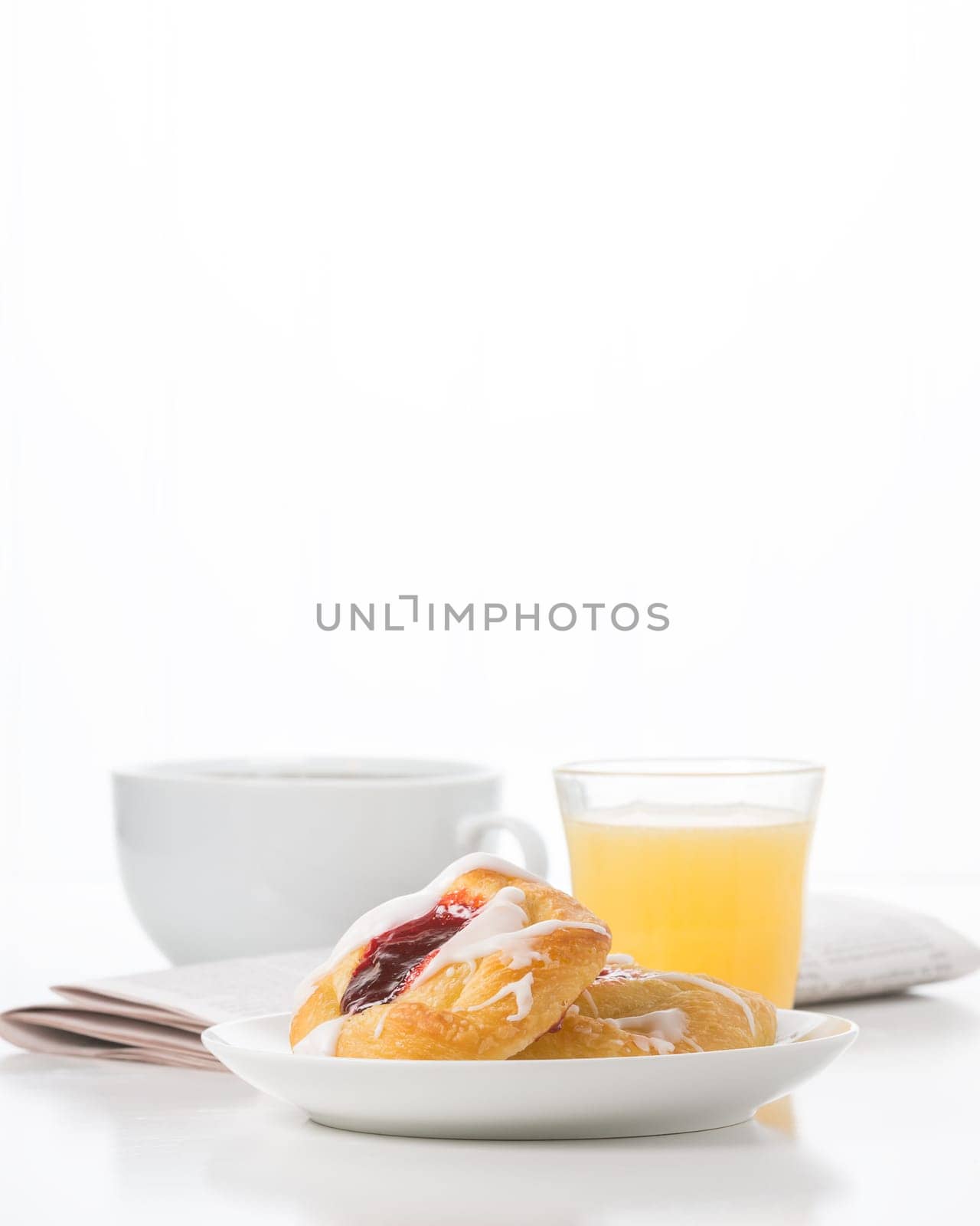 Fresh raspberry danish and coffee with the morning newspaper in the background.