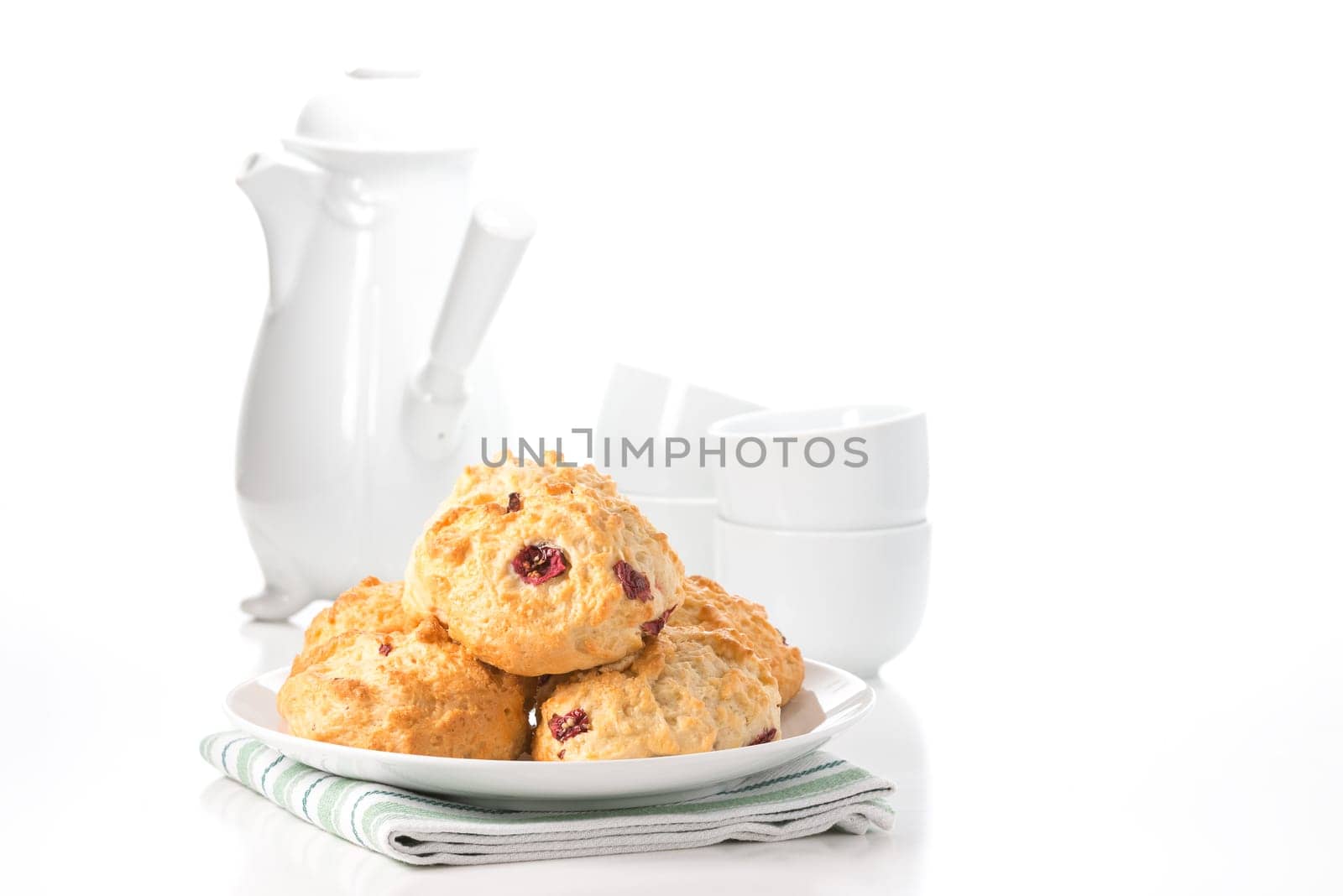 Fresh lemon cranberry scones with a coffee pot and cups in the background.