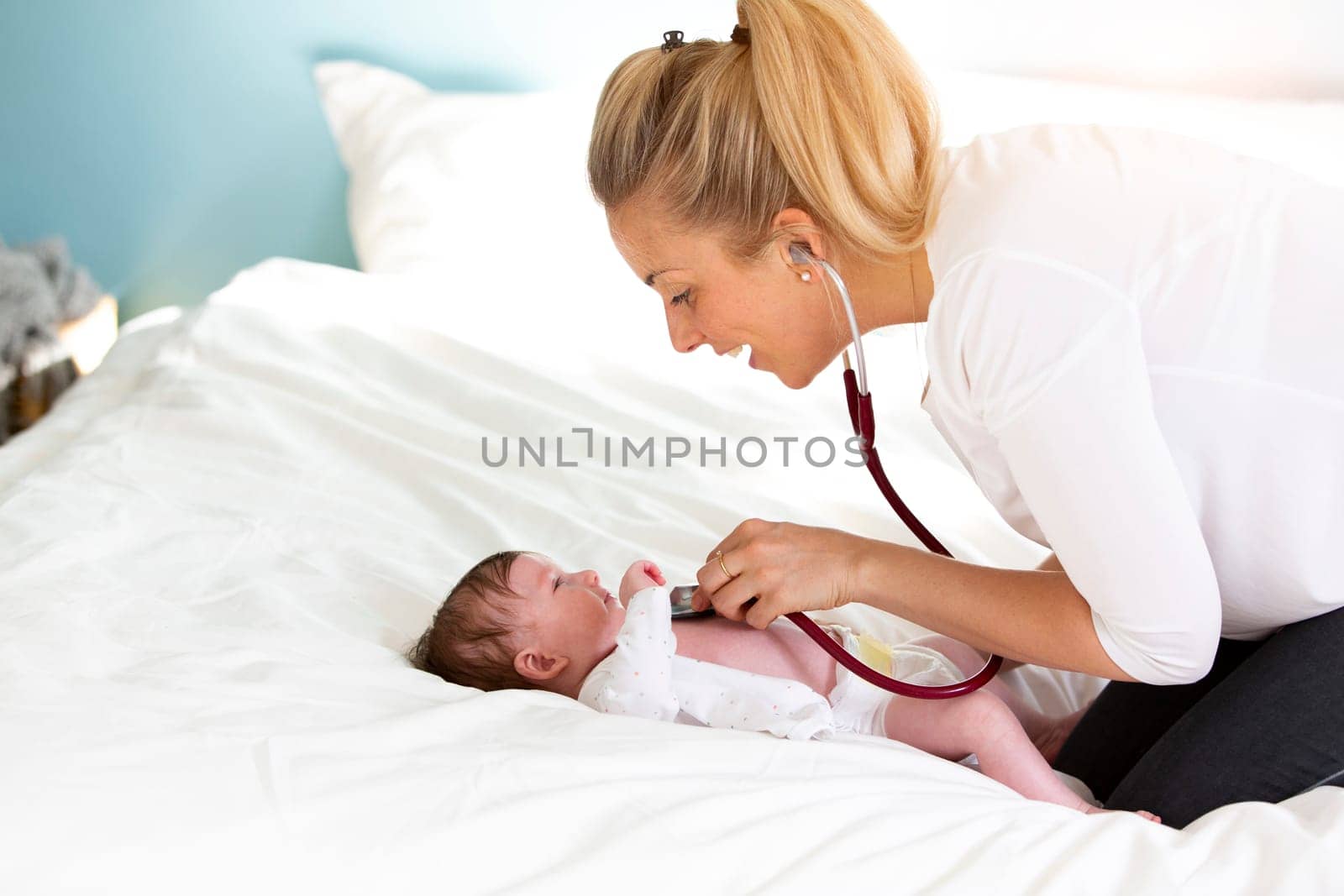 Pediatrician examines baby with stethoscope at home