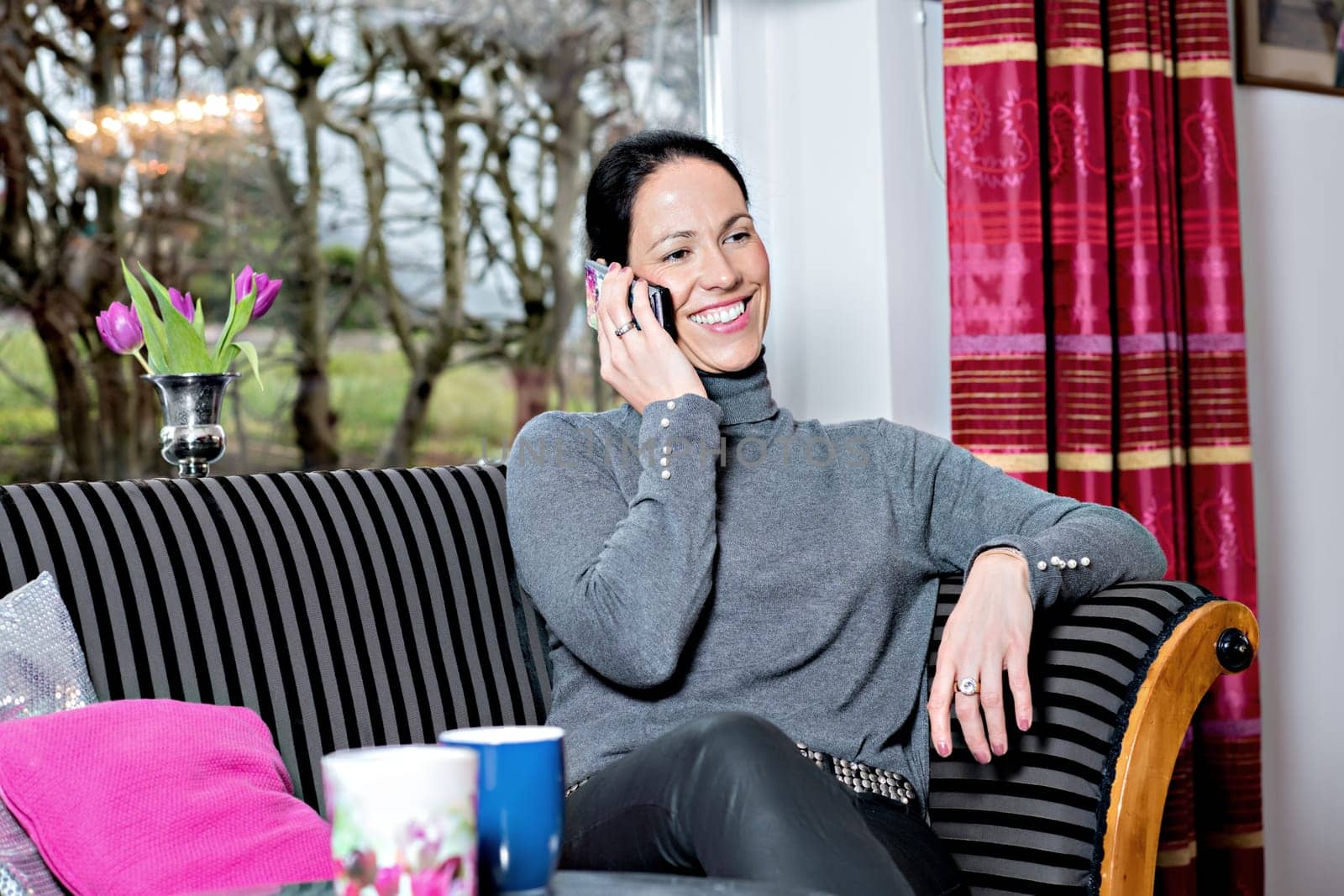 young dark haired woman at home sitting on sofa and calling