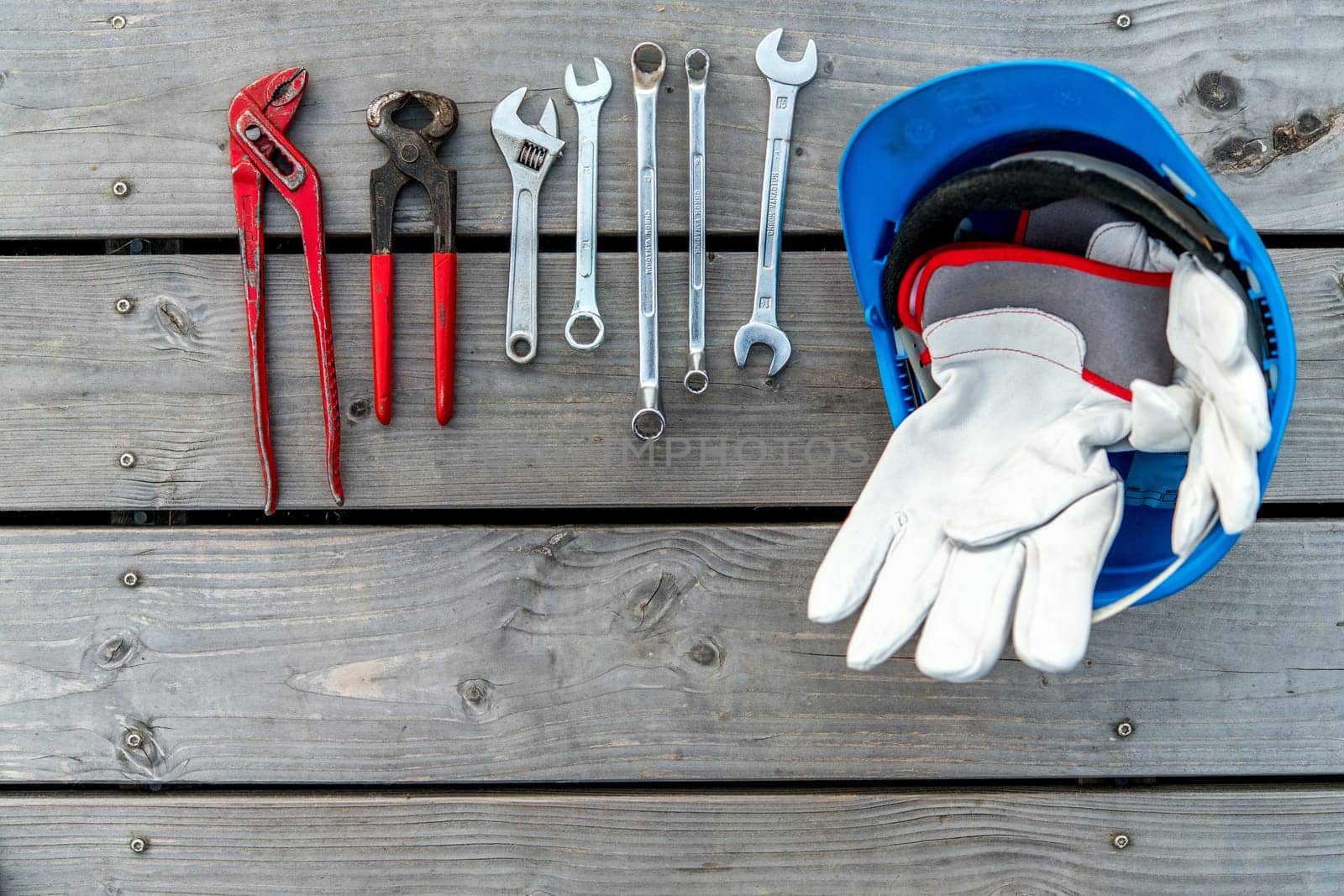 blue helmet different tools and work gloves on wooden ground