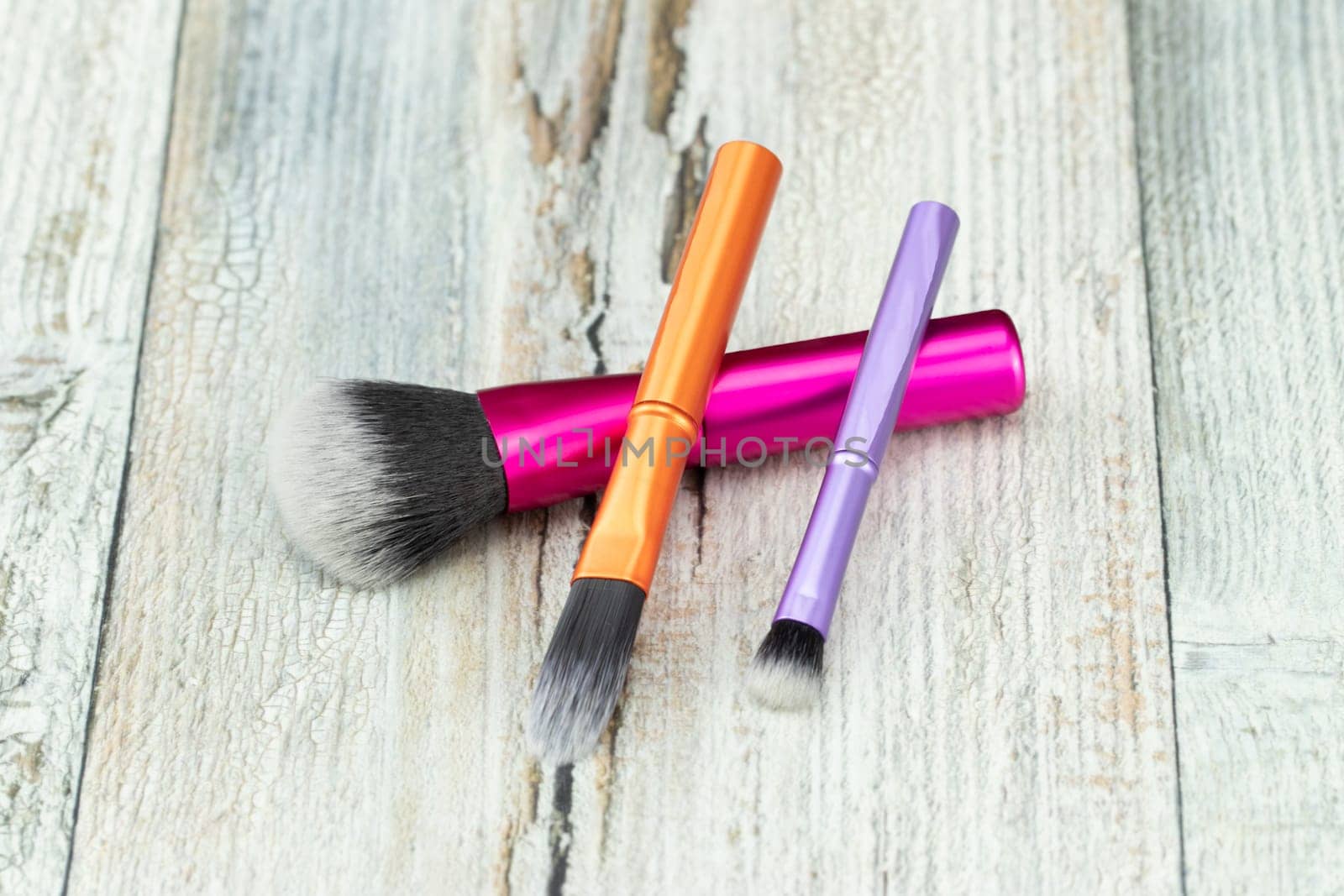 Set makeup brushes on rustic wooden table.