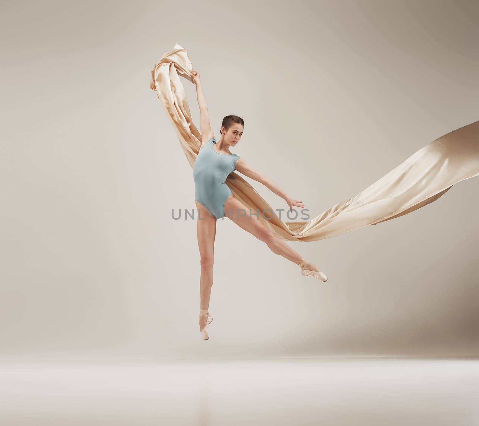 Modern ballet dancer exercising in full body on white studio background. Ballerina or female dancer with silk fabric dancing on white studio background. Caucasian model on pointe shoes