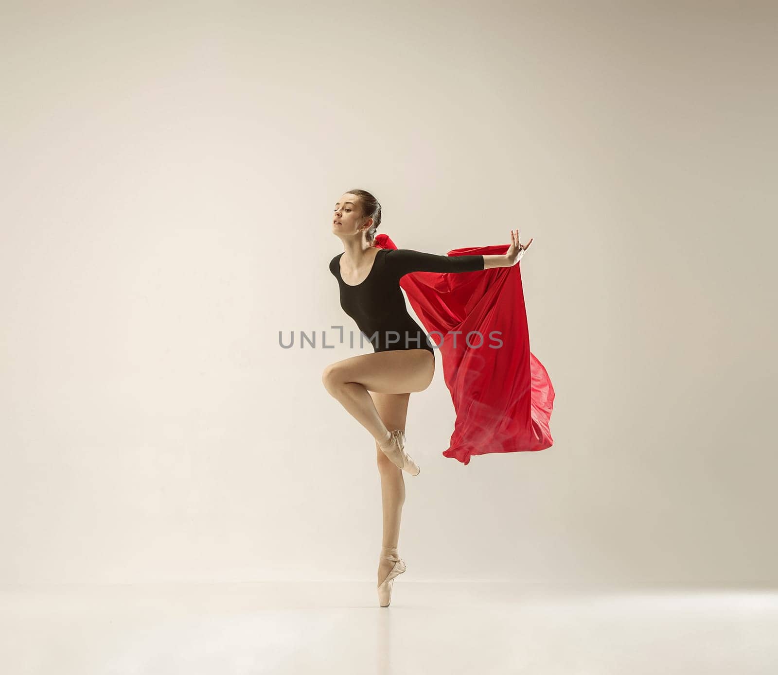 Modern ballet dancer exercising in full body on white studio background. Ballerina or female dancer with silk fabric dancing on white studio background. Caucasian model on pointe shoes