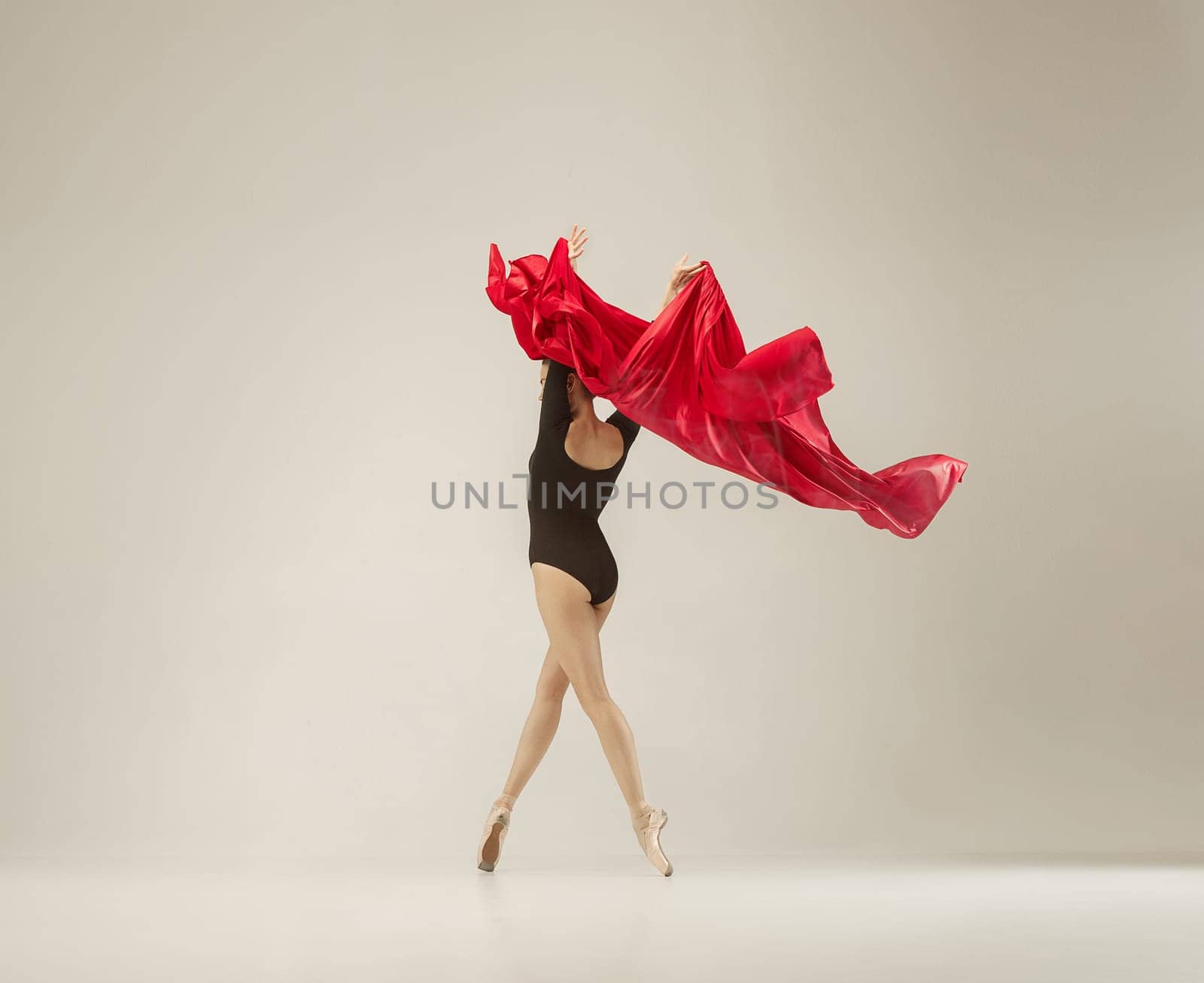 Modern ballet dancer exercising in full body on white studio background. Ballerina or female dancer with silk fabric dancing on white studio background. Caucasian model on pointe shoes