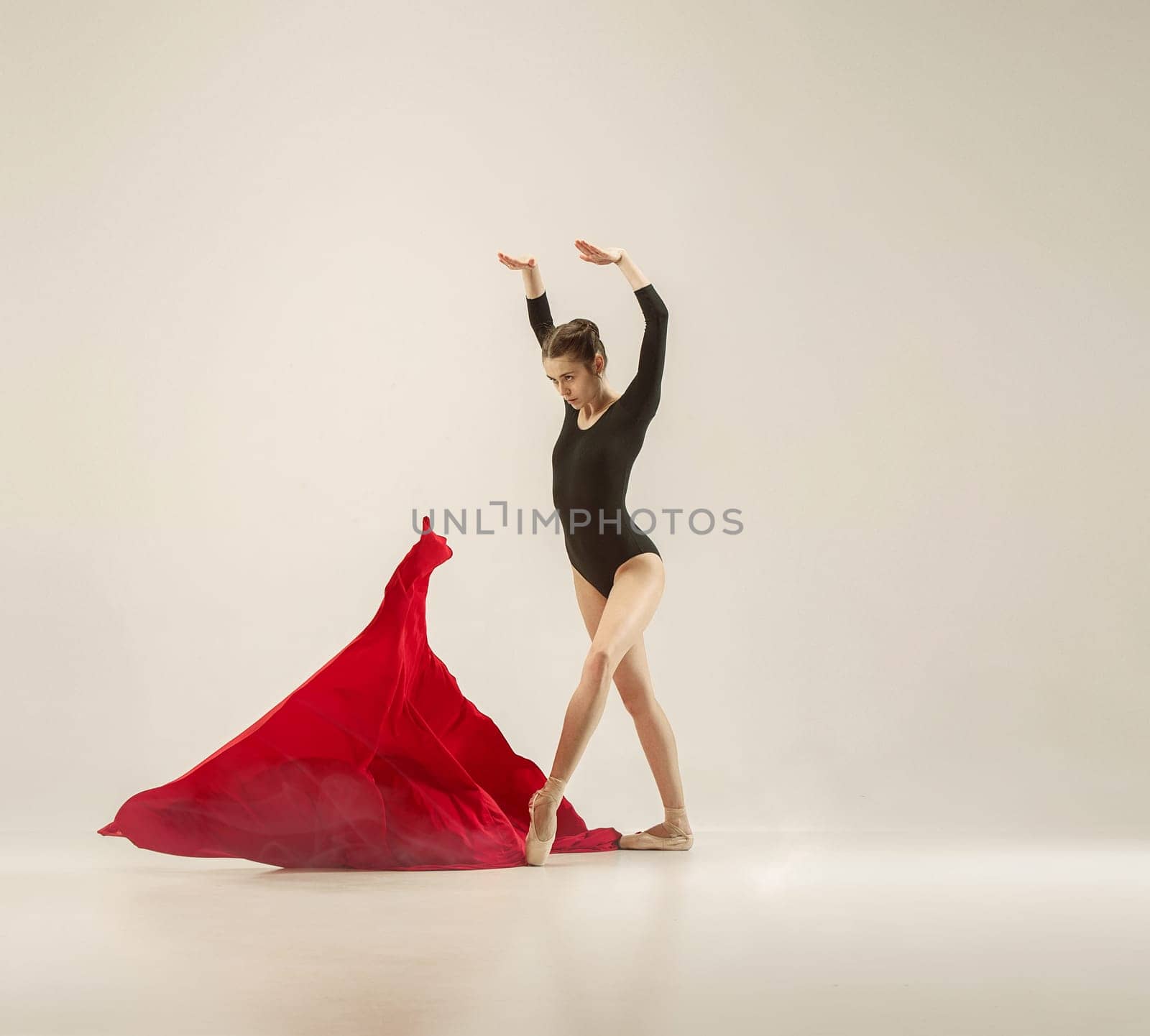 Modern ballet dancer exercising in full body on white studio background. Ballerina or female dancer with silk fabric dancing on white studio background. Caucasian model on pointe shoes