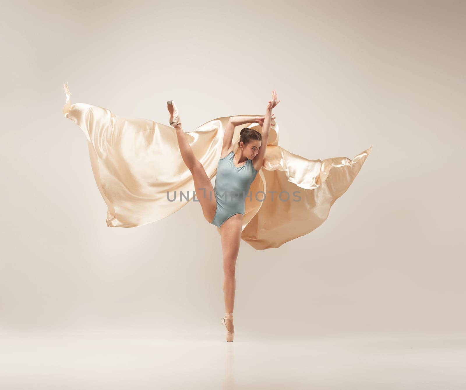 Modern ballet dancer exercising in full body on white studio background. Ballerina or female dancer with silk fabric dancing on white studio background. Caucasian model on pointe shoes