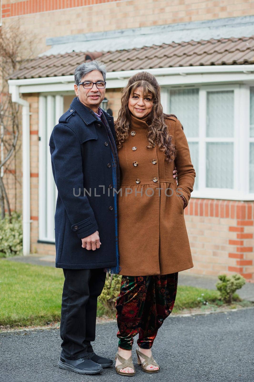 Full length portrait of a happy mature couple on the driveway of their home.