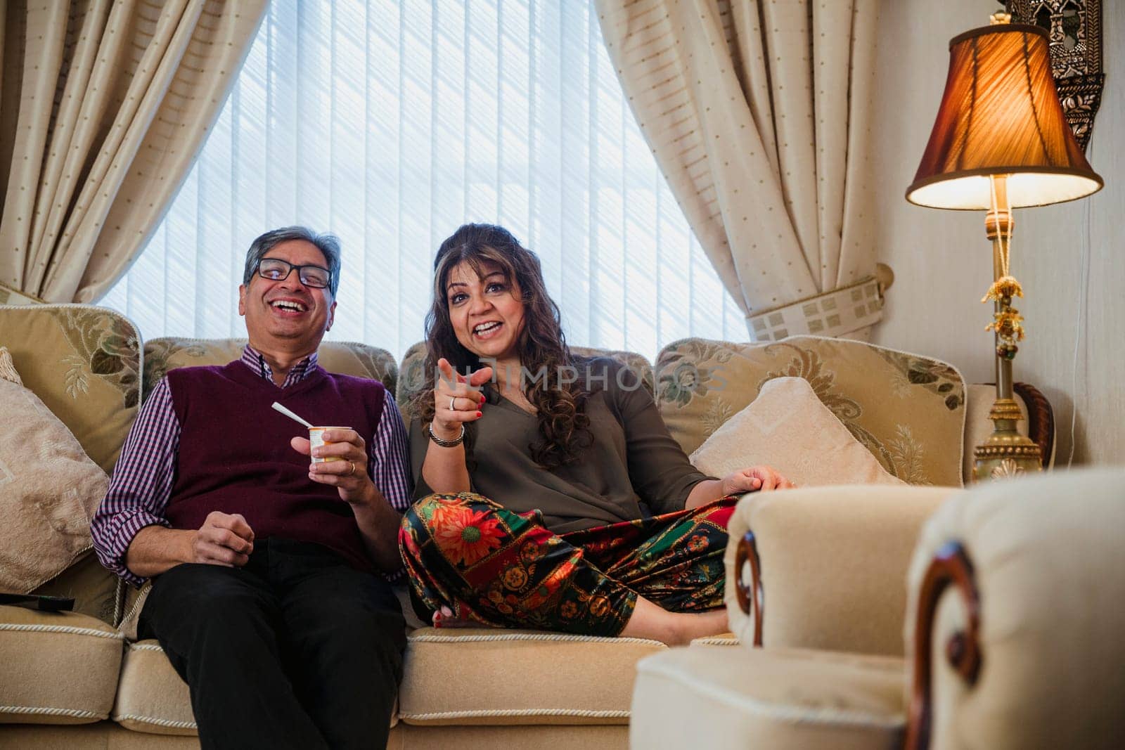 Mature couple are relaxing at home, watching television in the living room.