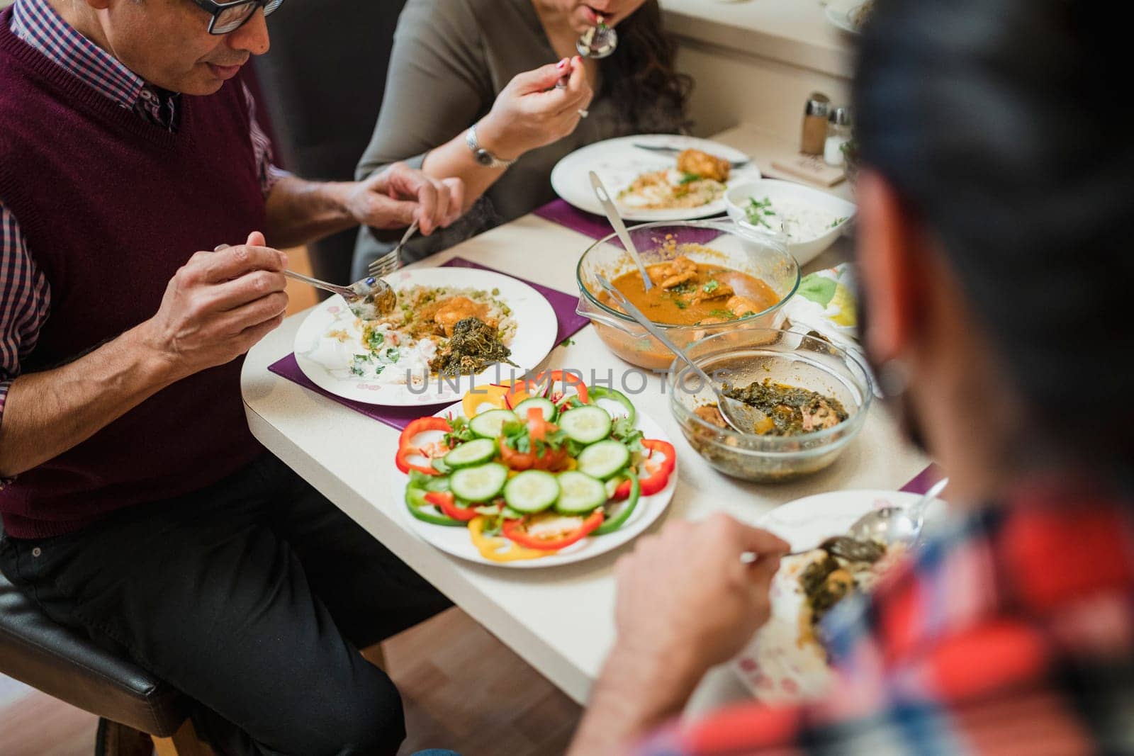 Close up shot of homemade indian food on a family dining table. They are eating curry with salad.