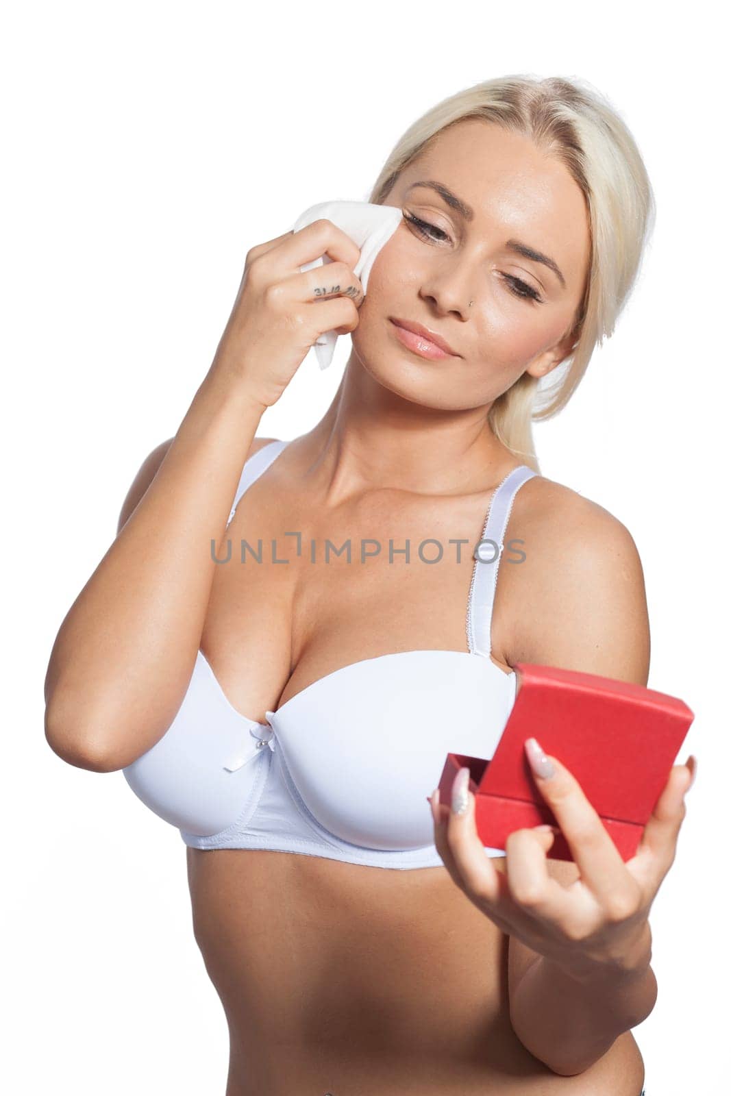 Young woman clean face and eyes with wet wipes, holding mirror, remove make-up, body breast lingerie