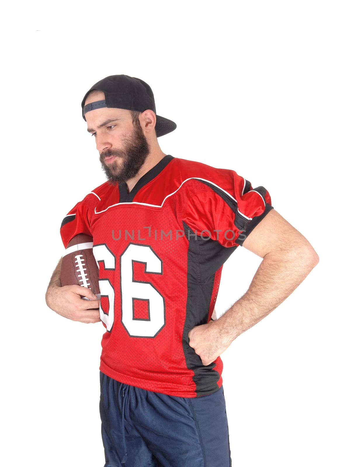 A close-up image of a football player in his jersey, holding his football.and looking down, thinking, isolated for white background.