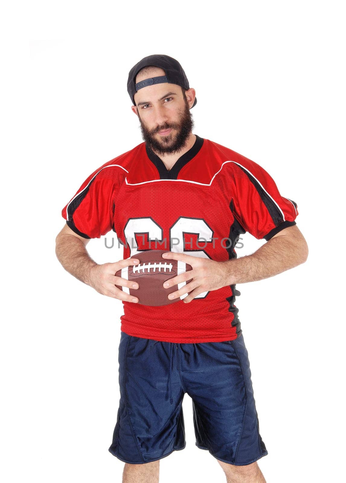 A handsome young football player standing with his ball in his hand.thinking of his next move in the game, isolated for white background.