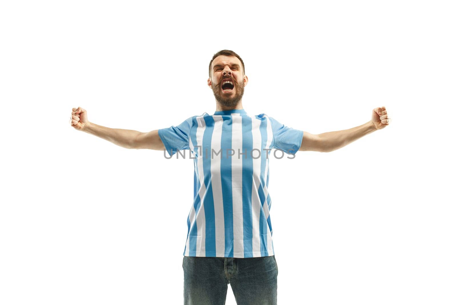 The young Argentinean fan celebrating on white background. The young man in soccer football uniform as winner isolated at white studio. Fan, support concept. Human emotions concept.