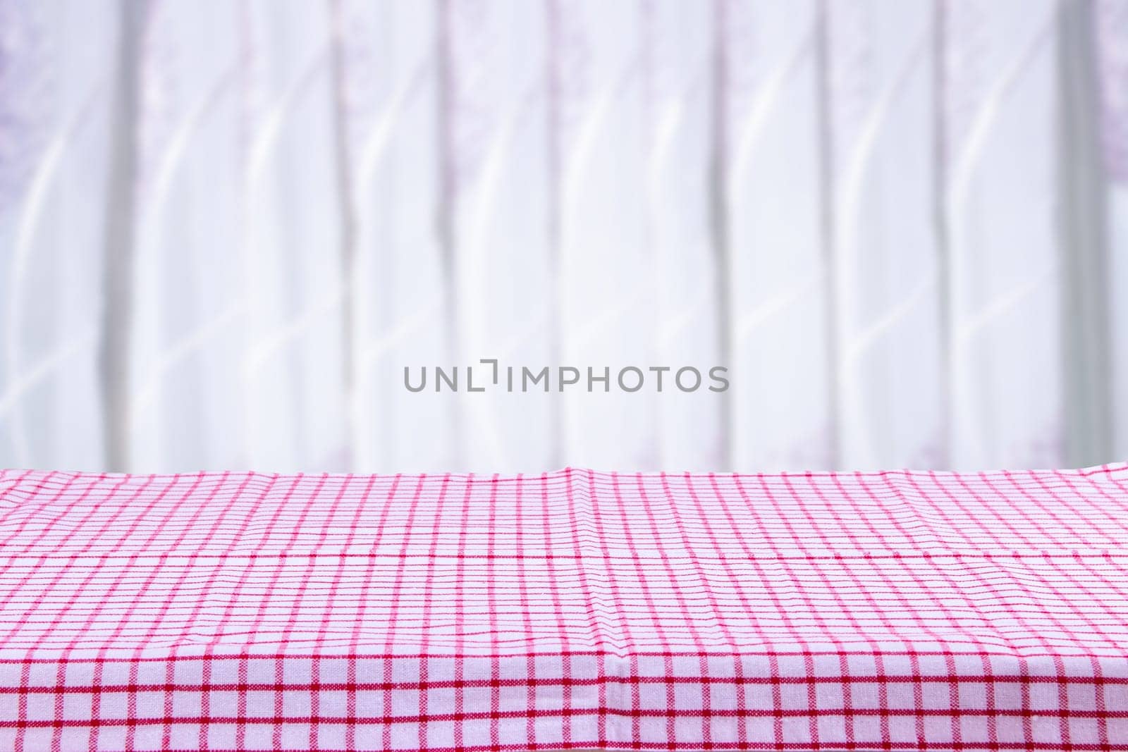 Empty table with red checkered tablecloth with bright background.  For food and product display montage.