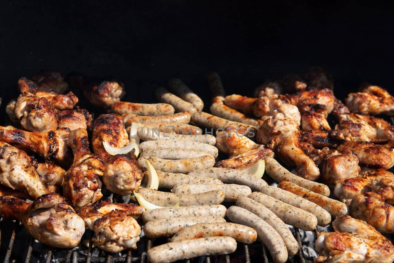 Chicken meat and sausages over the coals on a barbecue. Concept food. Close up.