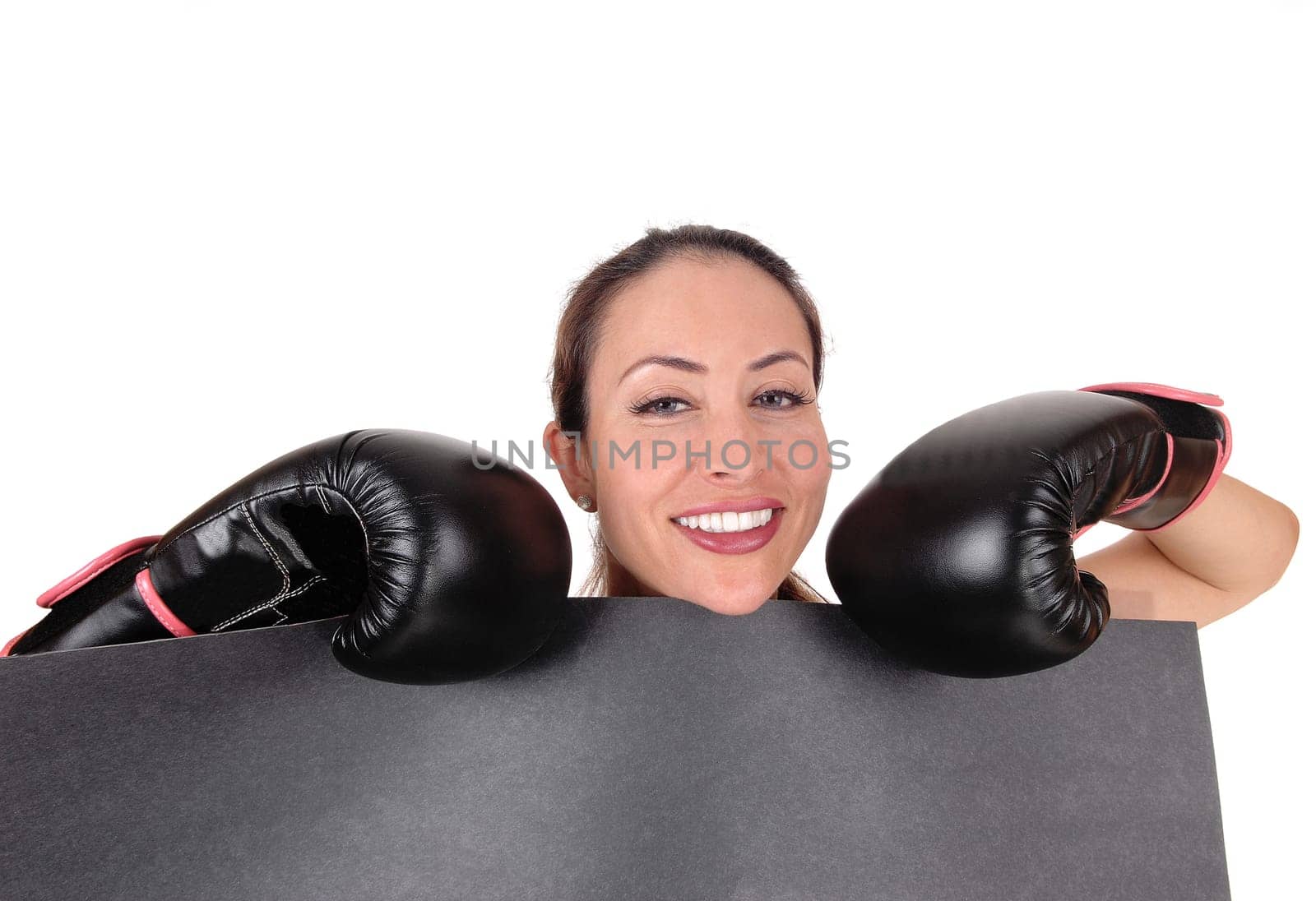 A young gorgeous woman with black boxing gloves holding a black.board looking over and smiling, isolated for white background.