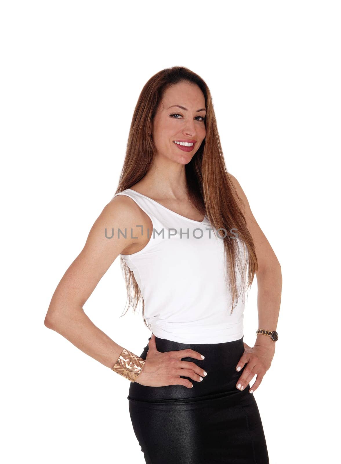 A lovely smiling young woman standing in a white top and black.leather skirt with long brunette hair, isolated for white background.