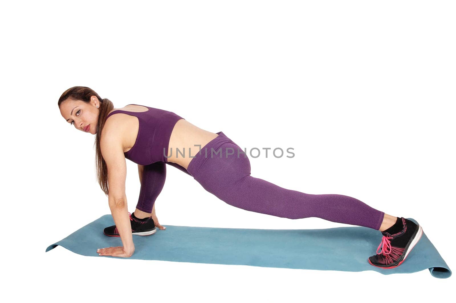 A tall slim woman exercising on a blue mat in a burgundy exercise.outfit, looking into the camera, isolated for white background.