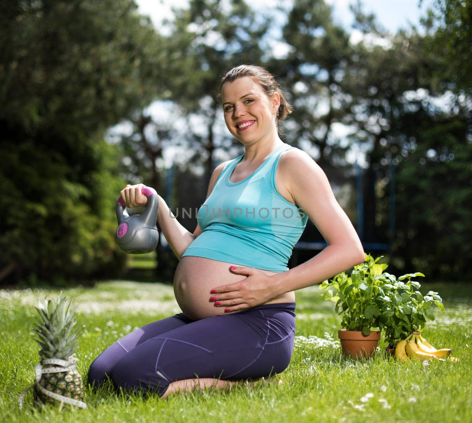 Pregnant woman doing fitness exercise on the grass