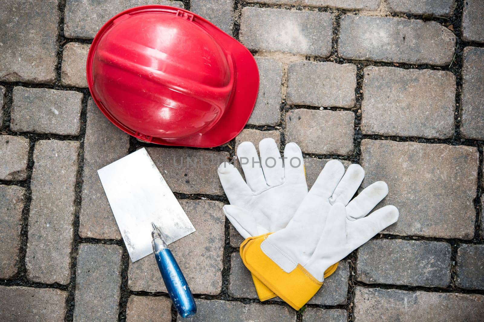 red helmet, trowel and work gloves on stones