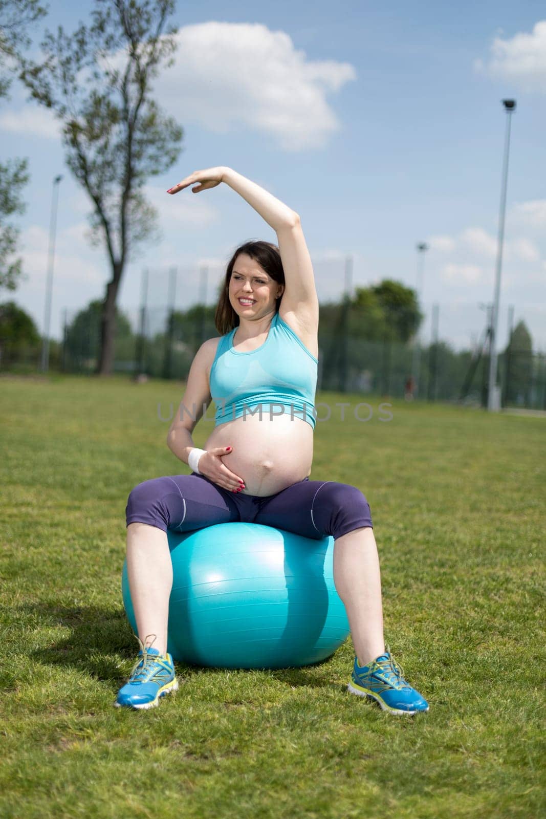 Beautiful young pregnant woman exercises with fitball in the gym