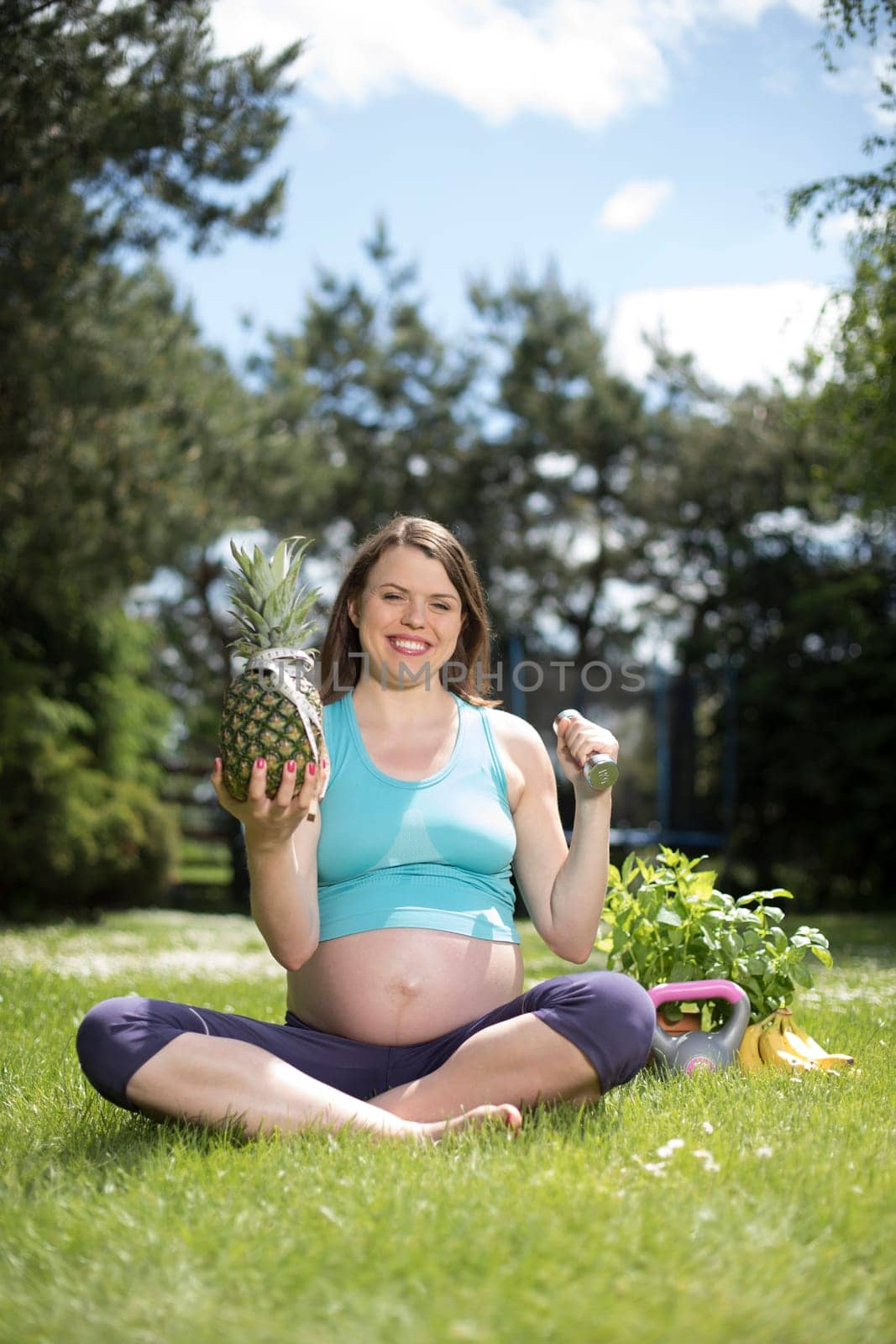 Pregnant woman doing fitness exercise on the grass