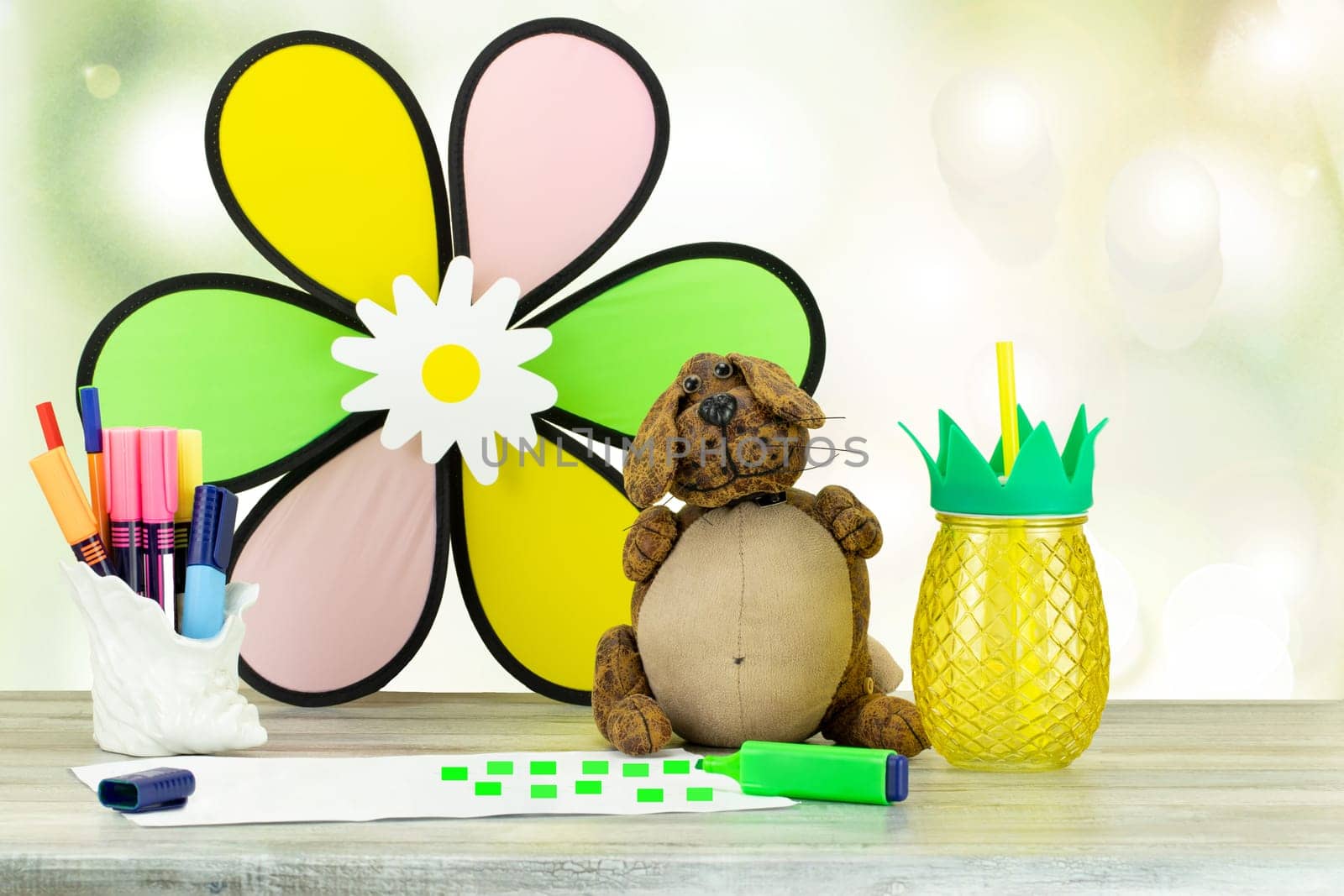 Happy children day. Workplace from child with funny dog, colorful pens a glass of juice with drinking straw and a painted drawing.  Space for your design.
