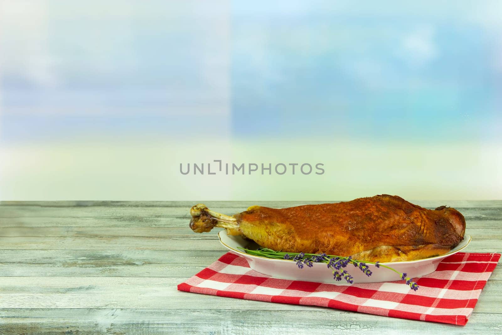 A roast turkey leg or drumstick  on rustic wooden table over bright blue sky backround. After cooking. Concept food.