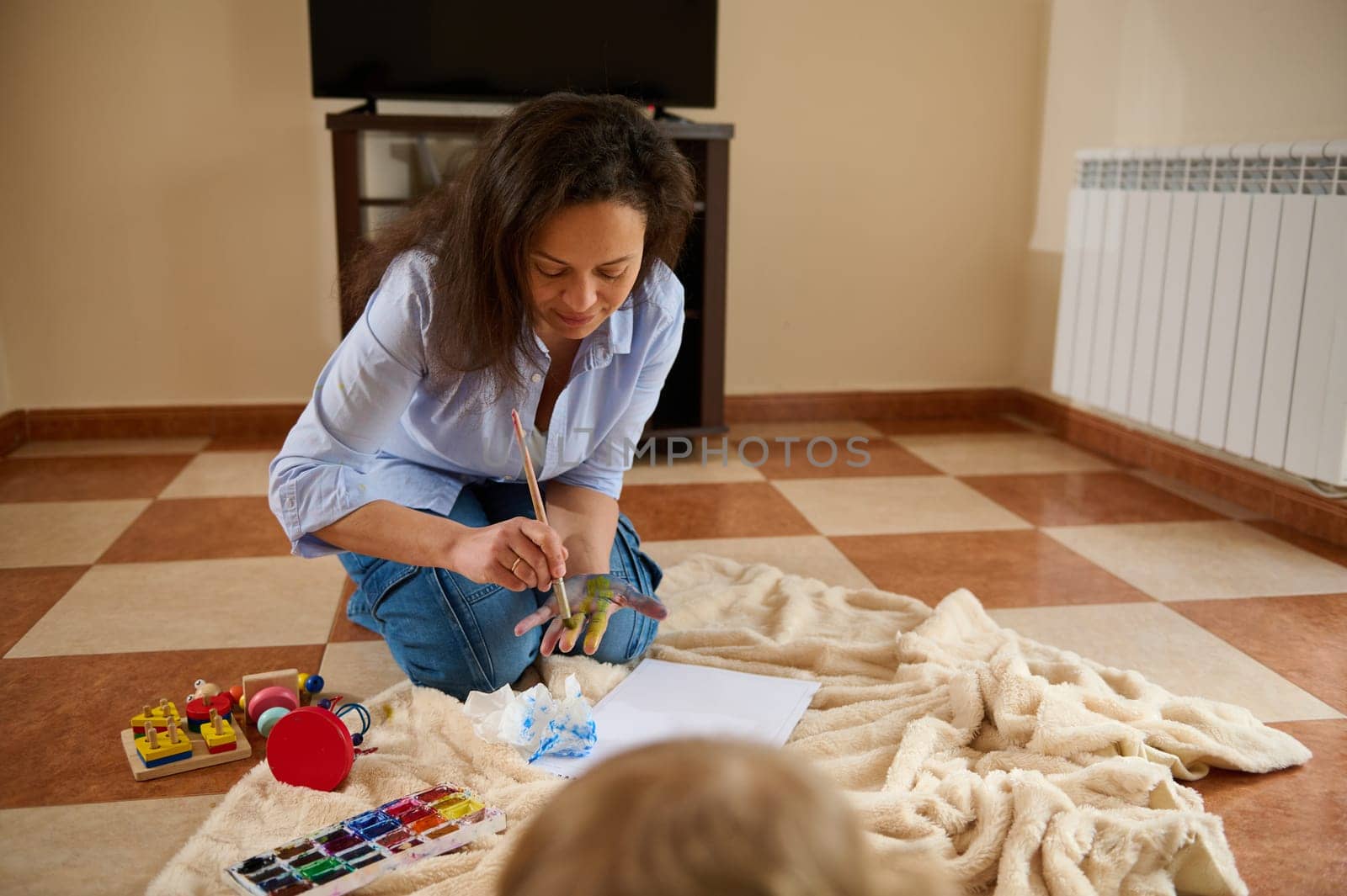 A mother spending quality time painting, exemplifying the joys of parenthood and creativity in a warm house setting.