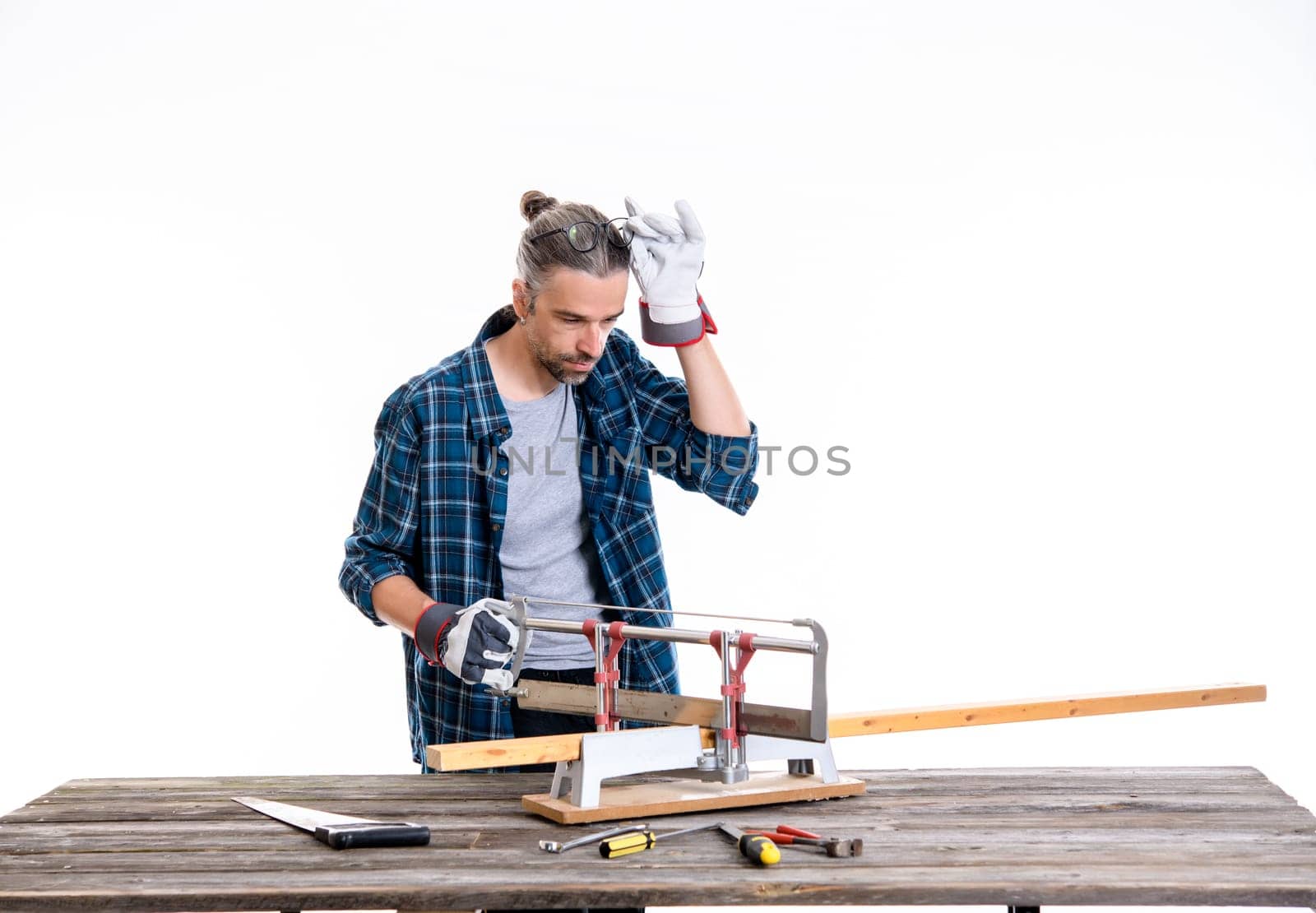 worker in blue plaid  shirt sawing wood