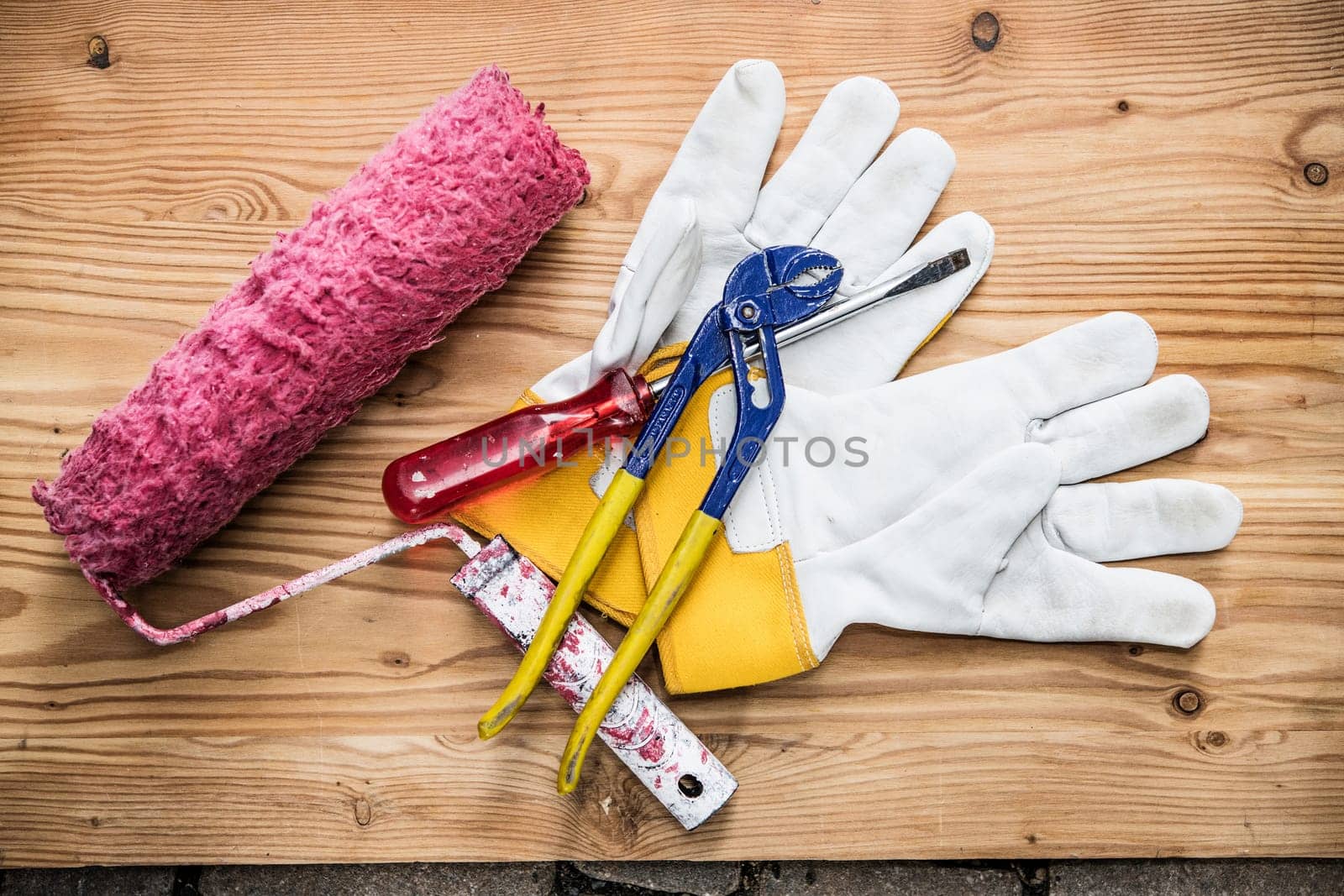 paint roller,tools and work gloves on wooden ground