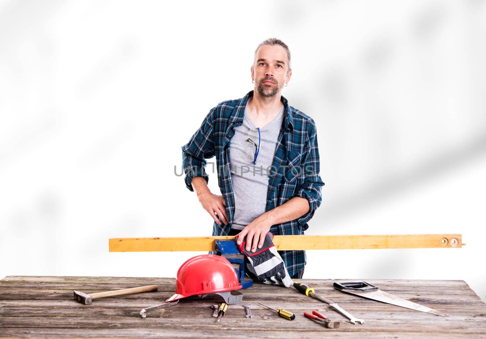 worker in blue plaid  shirt with red helmet on workbench
