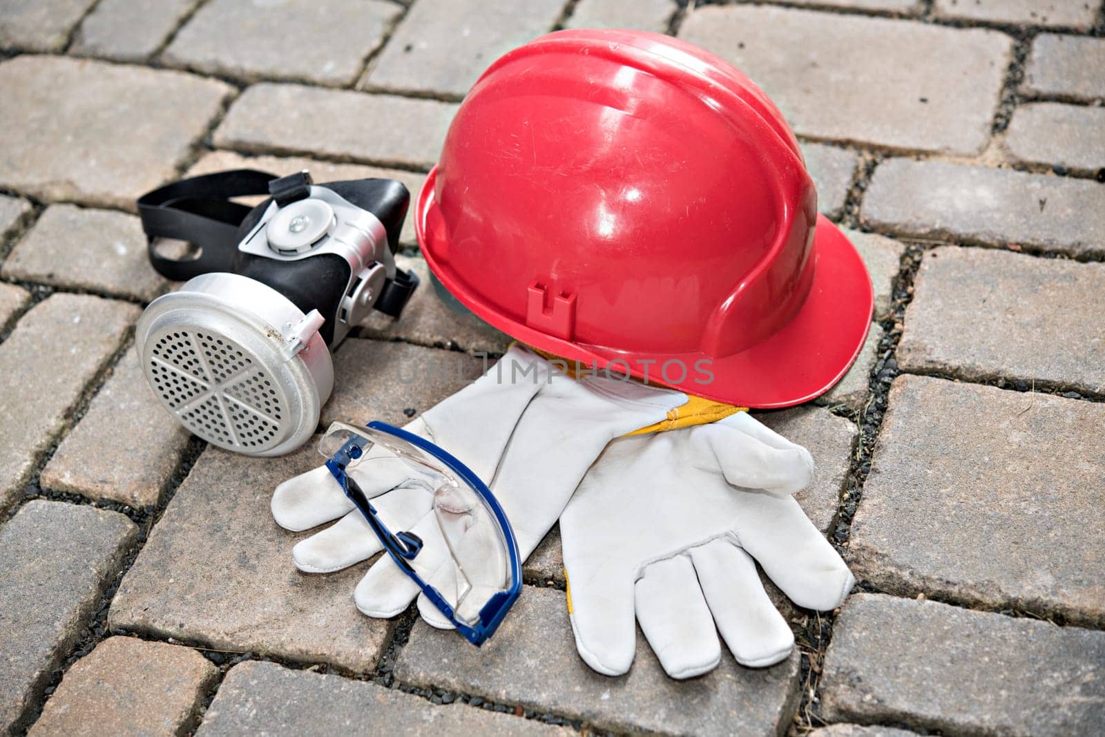 red helmet, respiratory mask,goggles and work gloves on stone ground