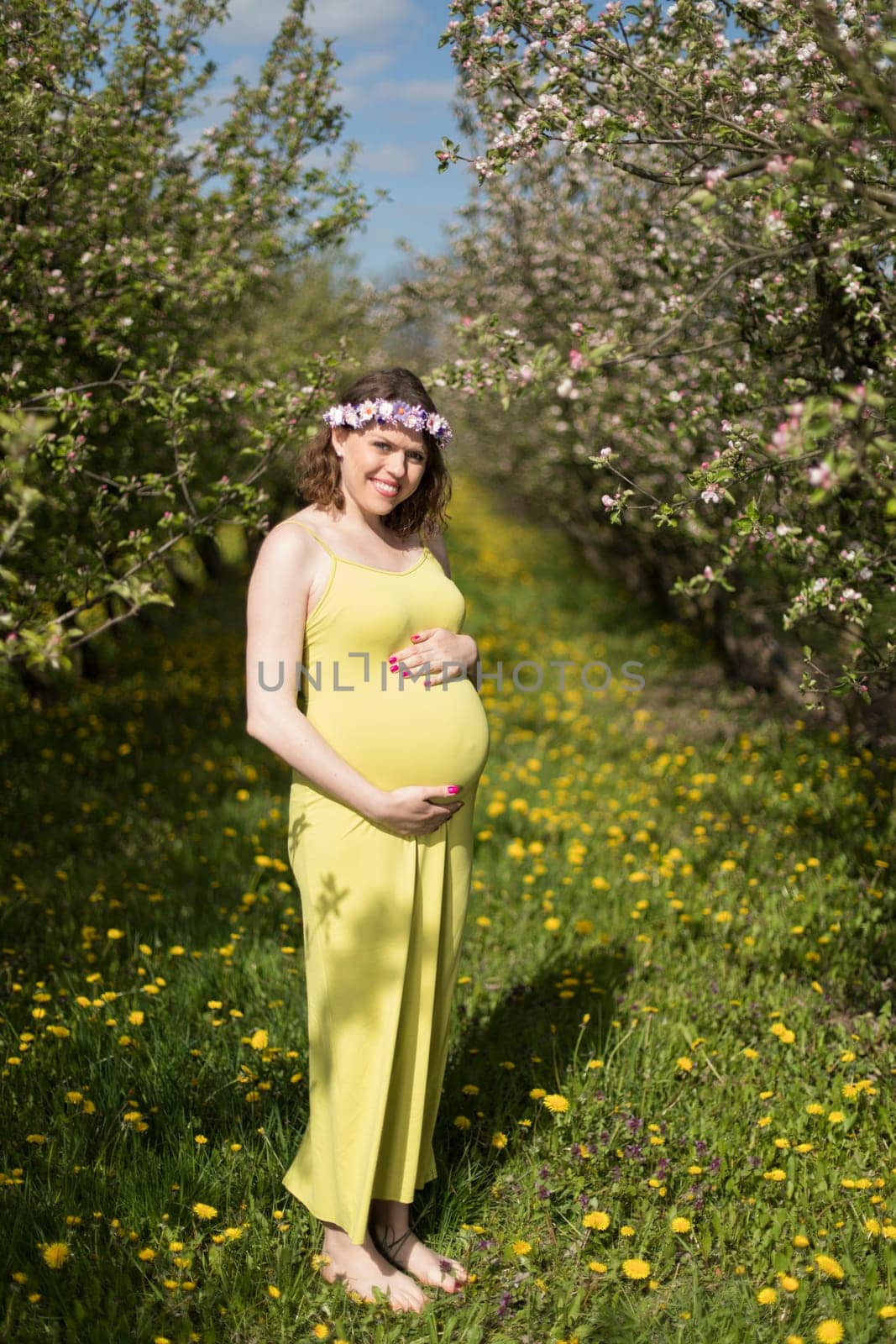 Young beautiful pregnant woman, blooming garden