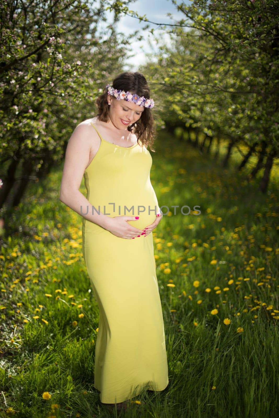 Young beautiful pregnant woman, blooming garden