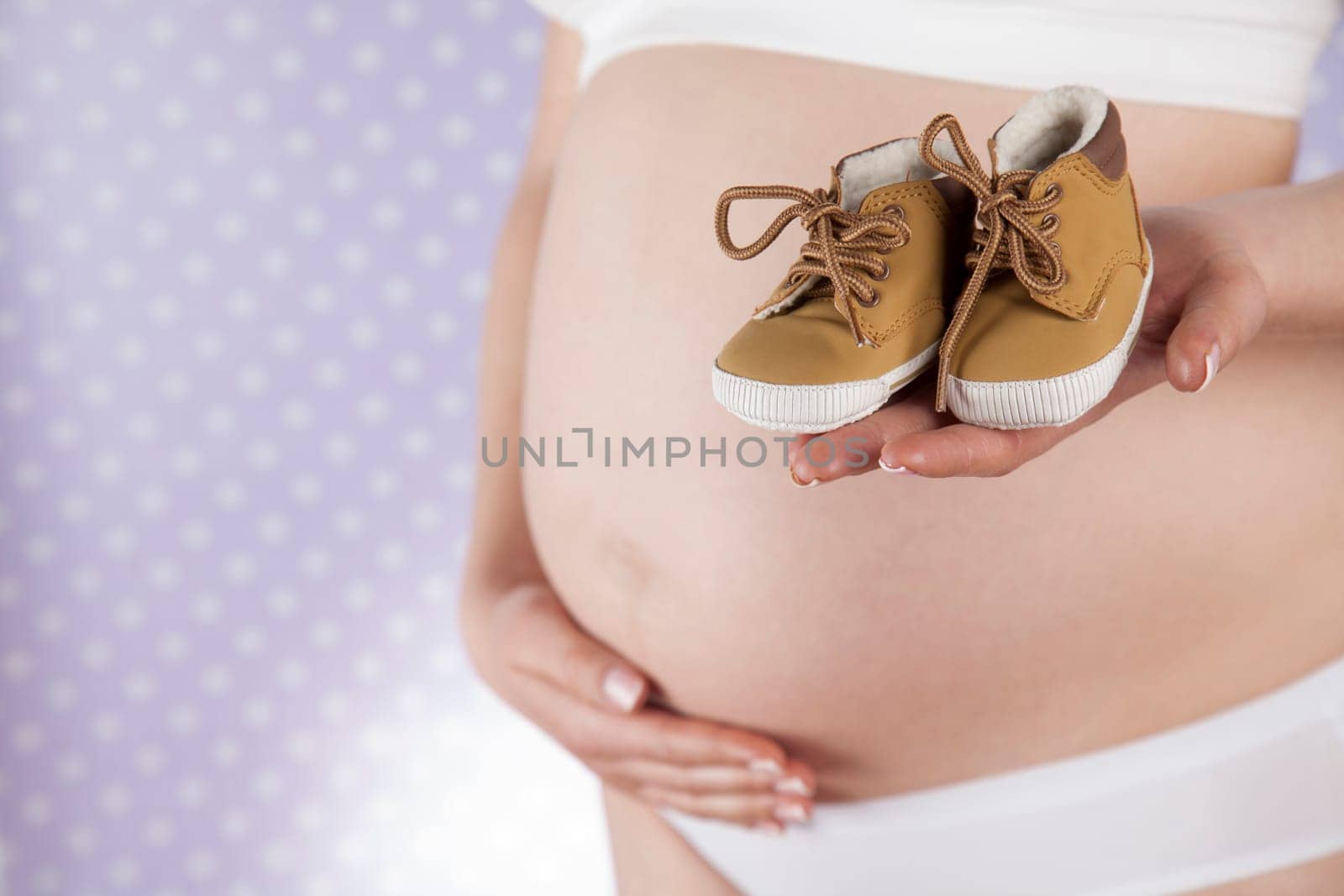 Pregnant woman holding baby shoes in her hands