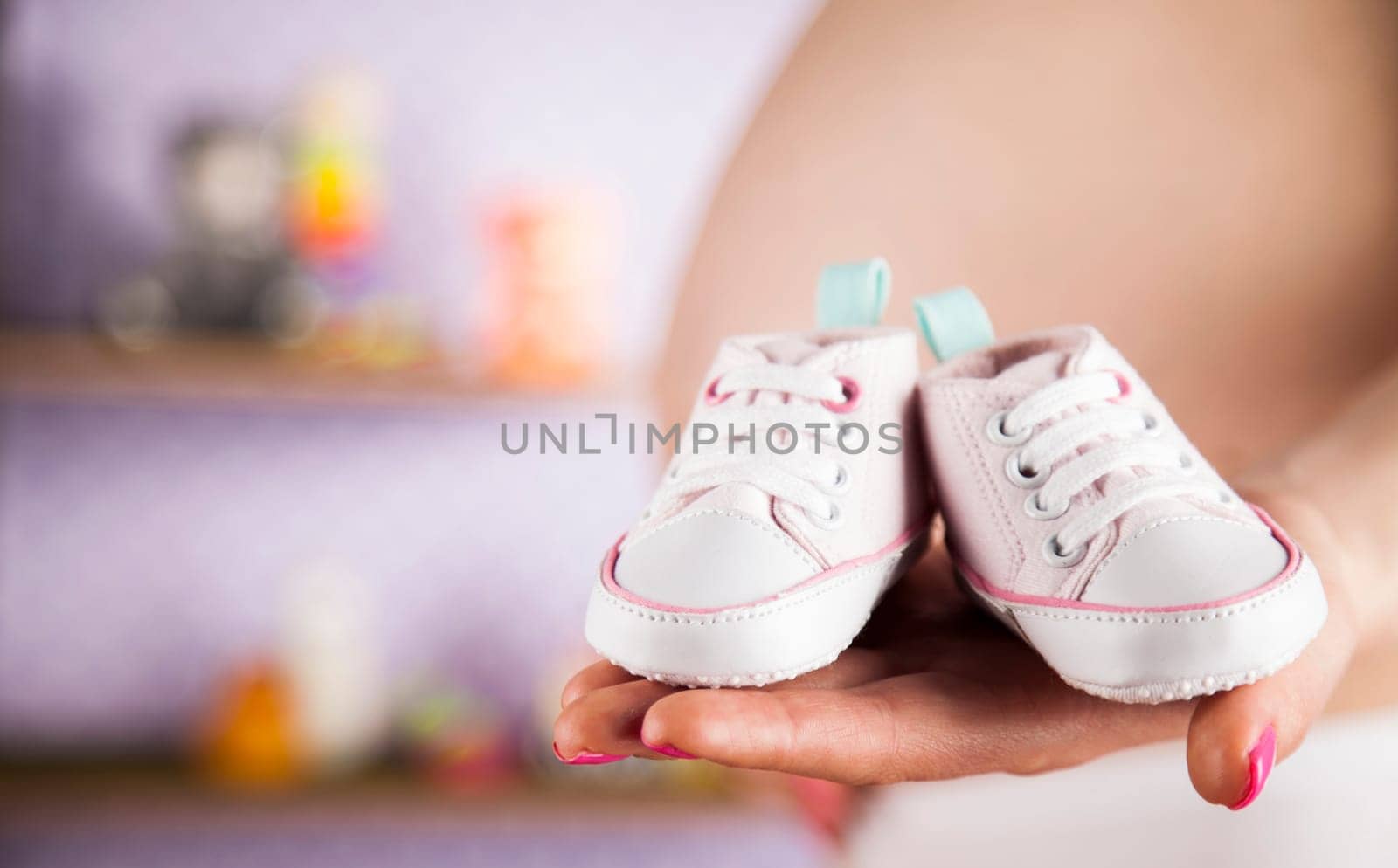 Pregnant woman holding baby shoes in her hands