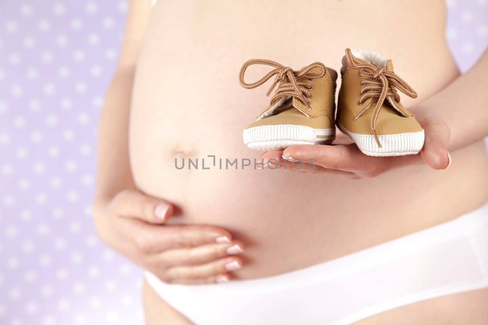 Pregnant woman holding baby shoes in her hands