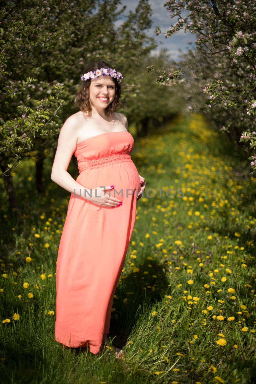 Young beautiful pregnant woman, blooming garden